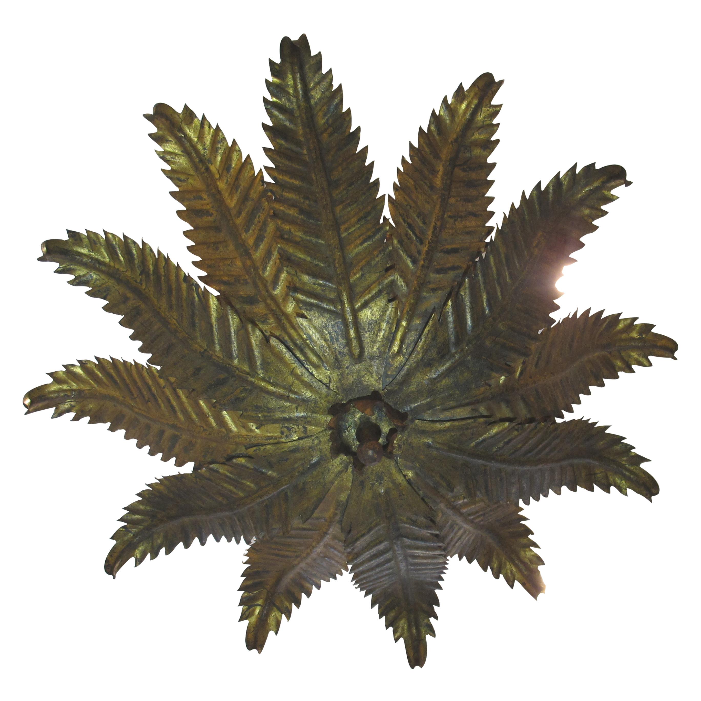 This ceiling light was made in Spain in the 1950s and is crafted from toleware. Designed to resemble a cluster of fern leaves, the fixture features hand-cut metal fronds arranged in layers, with a gold patinated finish that imparts a natural, aged