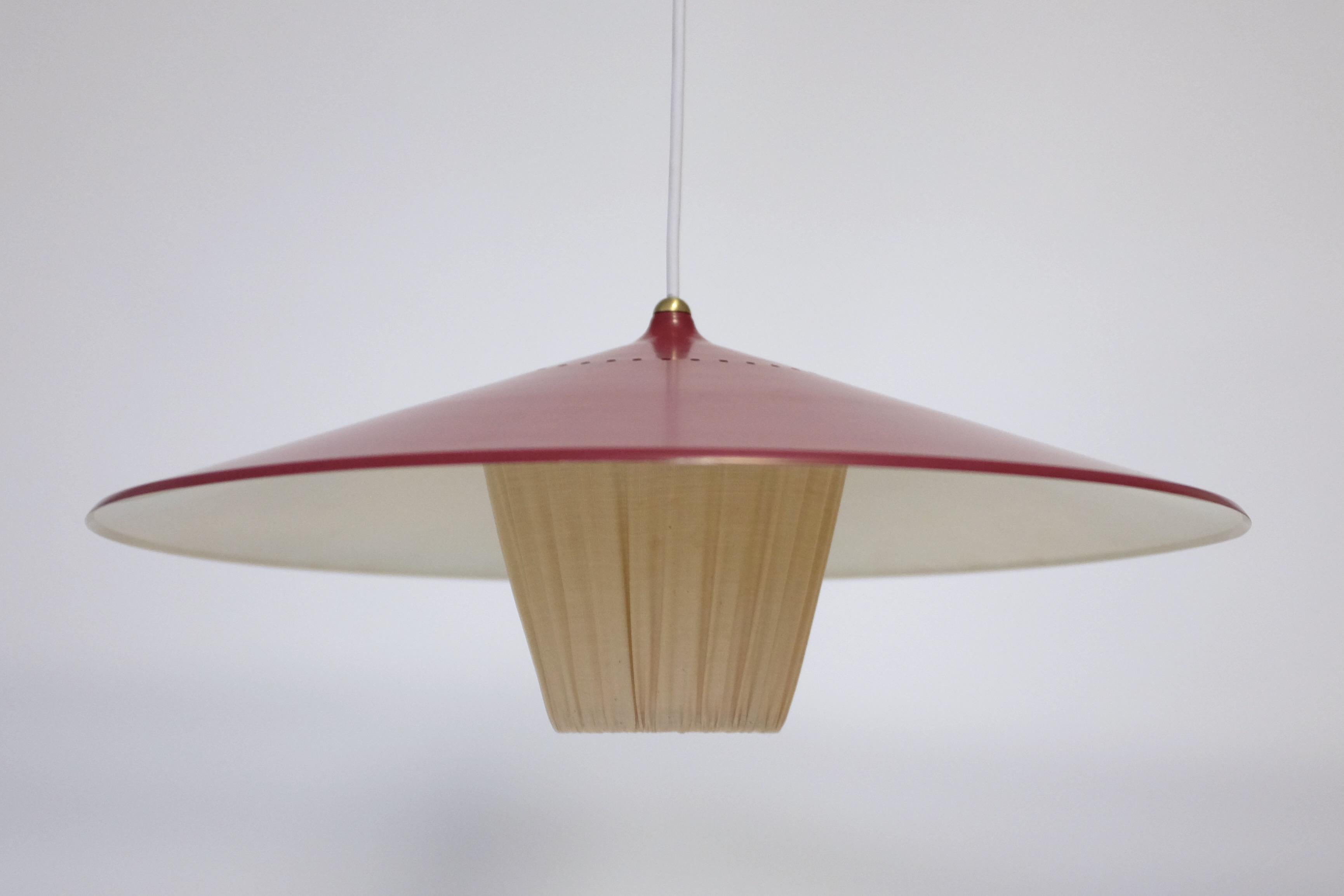 Vintage 1950s Swedish ceiling lamp possibly by Bergboms, Sweden. Beautiful red colored on the lamp shade with brass details and a cream colored fabric pendant underneath which focuses the light. Adjustable height through the cord with a total length