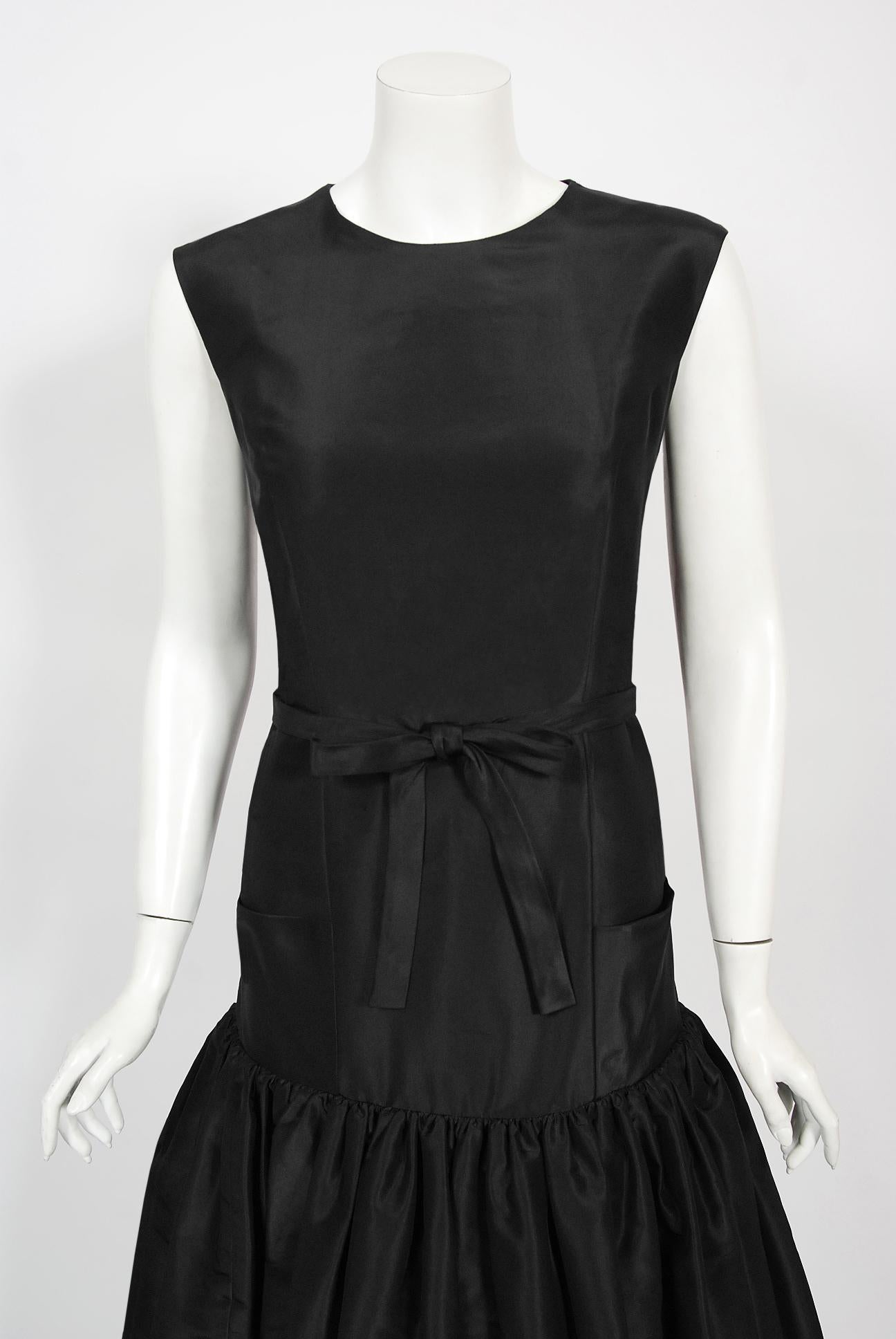 An incredibly chic and totally timeless Traina-Norell for I. Magnin designer cocktail dress dating back to their 1956 couture collection. Fashioned in a luxurious mid-weight black silk faille, this rare garment exemplifies their signature blend of