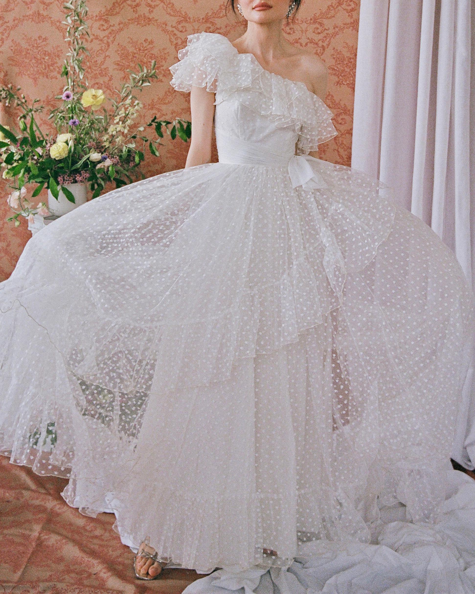 This absolutely stunning vintage 1950s tulle one-shoulder gown is unmatched in its romantic drama, and completely unique— you won't find another one like it. The tulle is complete with Swiss dot flocking throughout, creating dimension alongside the