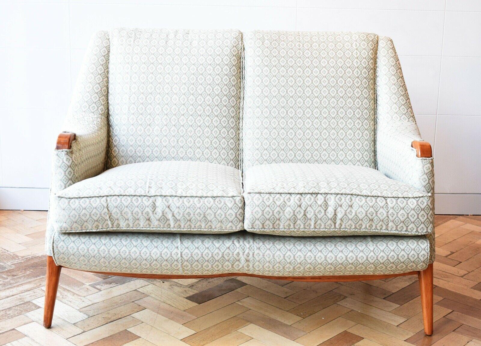 A pretty mid 20th century English two seater sofa, circa 1950s.

This sofa is of petite proportions, with teak tapered legs and exposed wooden 'elbows' similar to a Hans Wegner design feature. 

This piece has been reupholstered in a subtle