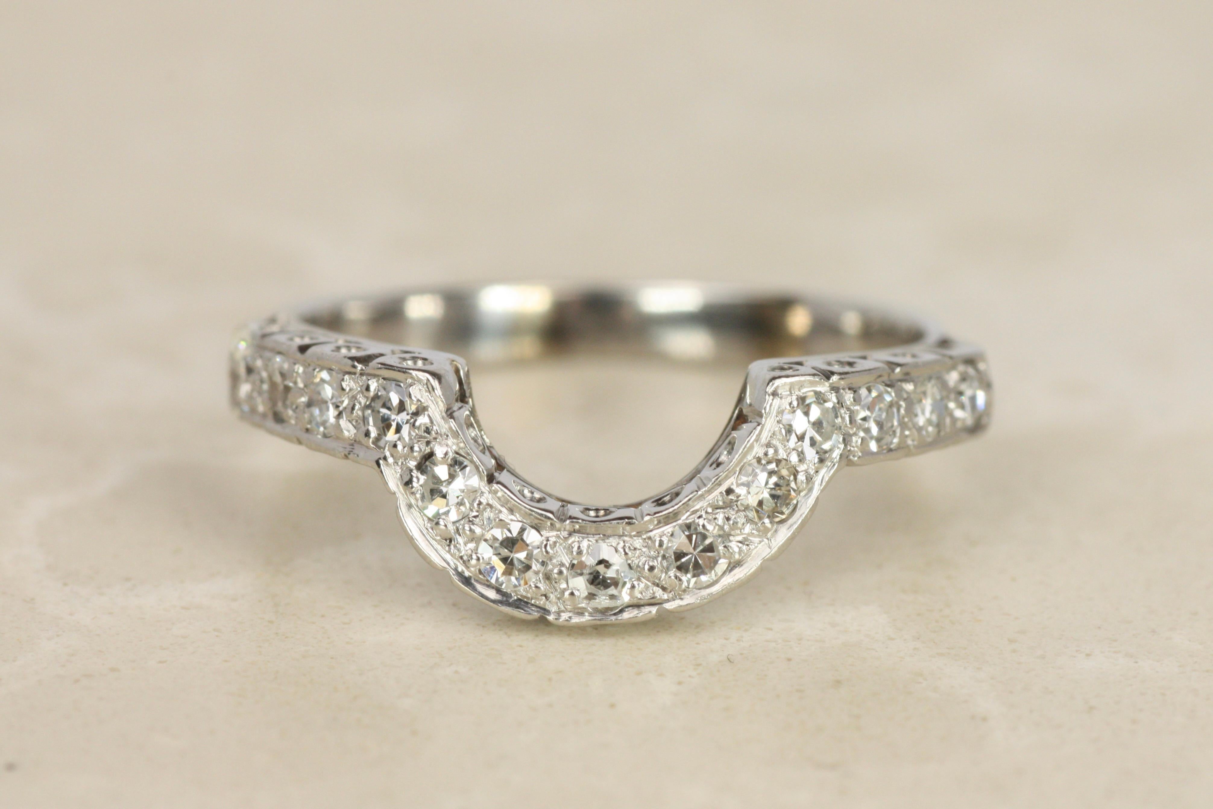 Esta alianza anidada de diamantes vintage de los años 50 presenta una distintiva curva en forma de U para encajar perfectamente alrededor de un anillo de compromiso. Está engastado con 13 diamantes redondos de talla única en un engaste de oro blanco