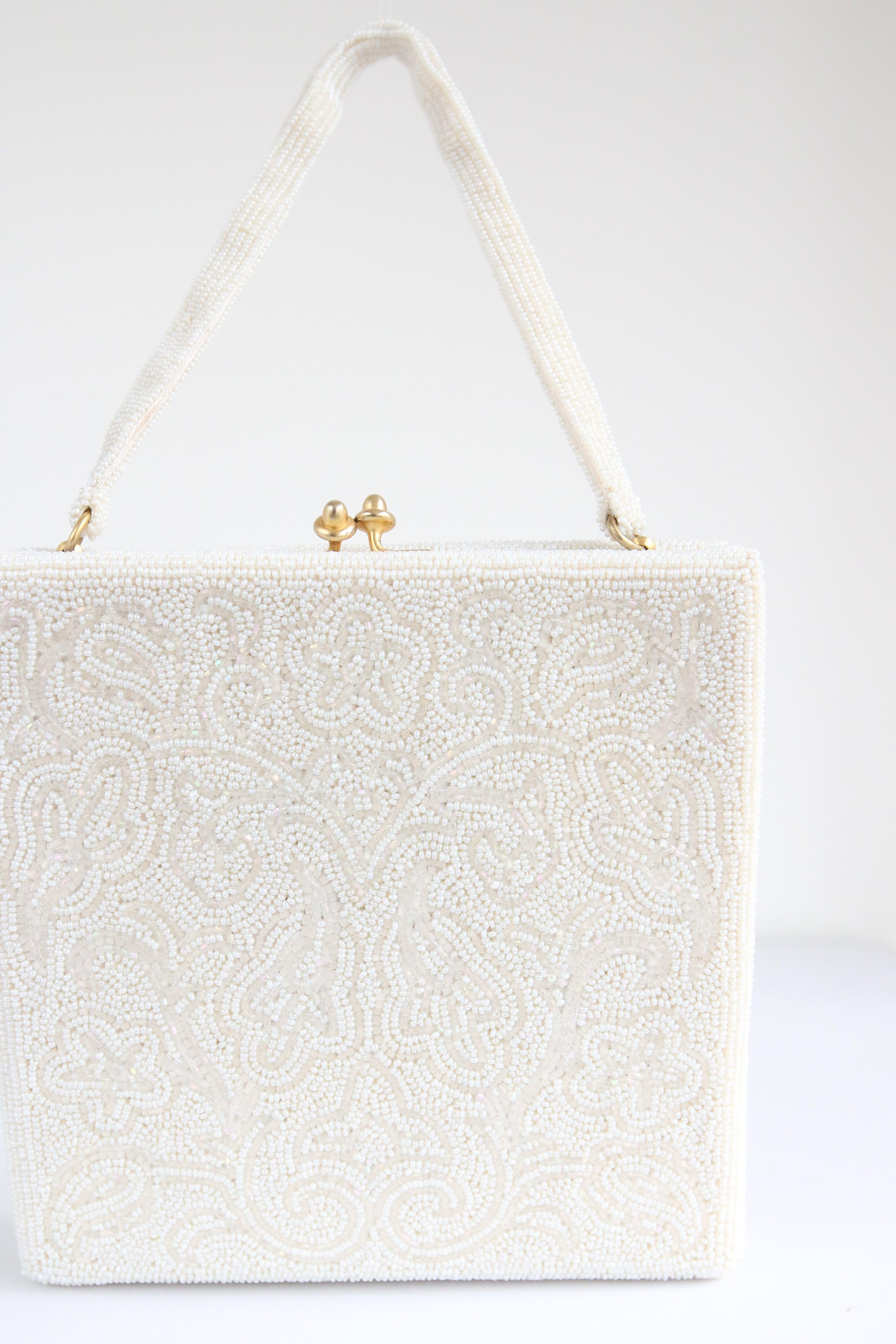 This truly enchanting 1950's beaded handbag, embellished with white glass rocaille beads and iridescent glass bugle beads, in a floral design, is the perfect statement piece to add to your accessory collection.

The square shape of the bag, sets off