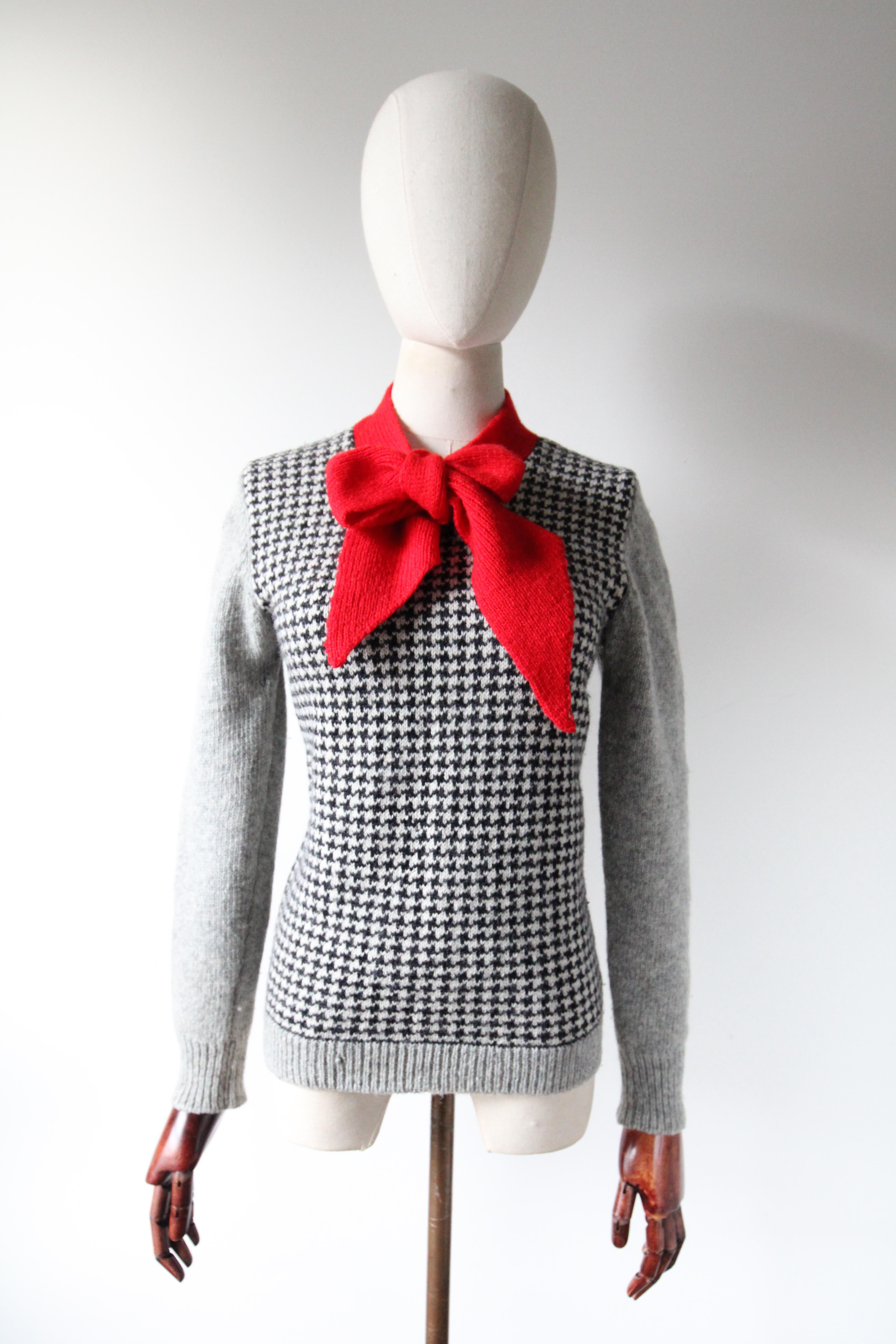 The perfect staple for the chillier months. Rendered in a black and white dogtooth pattern, with grey and red wool accents, this original 1950's knitted jumper is just the piece to keep the chill away.

The V shaped neckline is framed by a simple