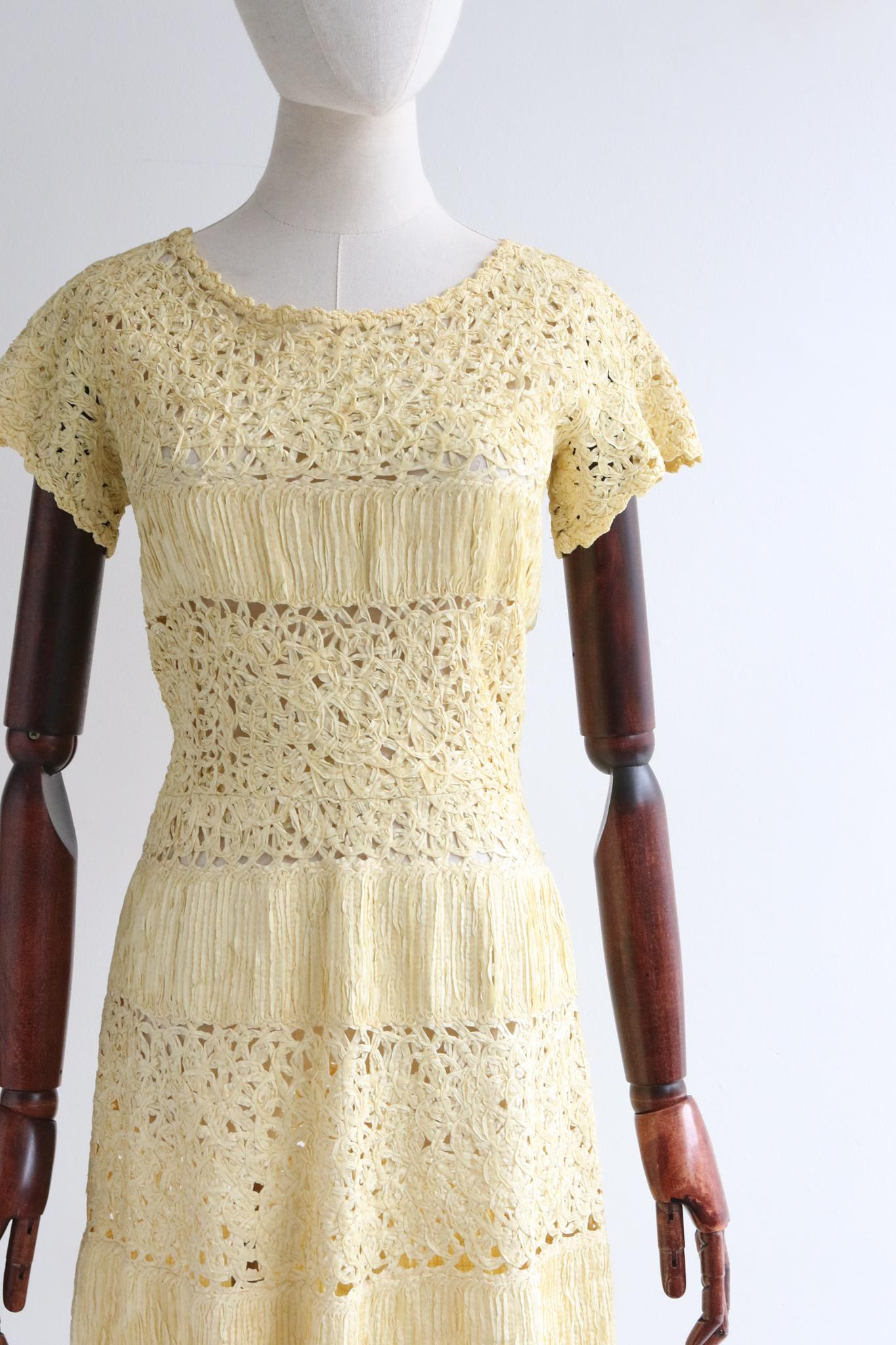 Realizzato nella morbidissima tonalità del giallo crema, questo originale abito con nastri degli anni '50 è il capo perfetto per dare il benvenuto alle stagioni più calde.

La sua scollatura arrotondata è incorniciata da dettagli smerlati con