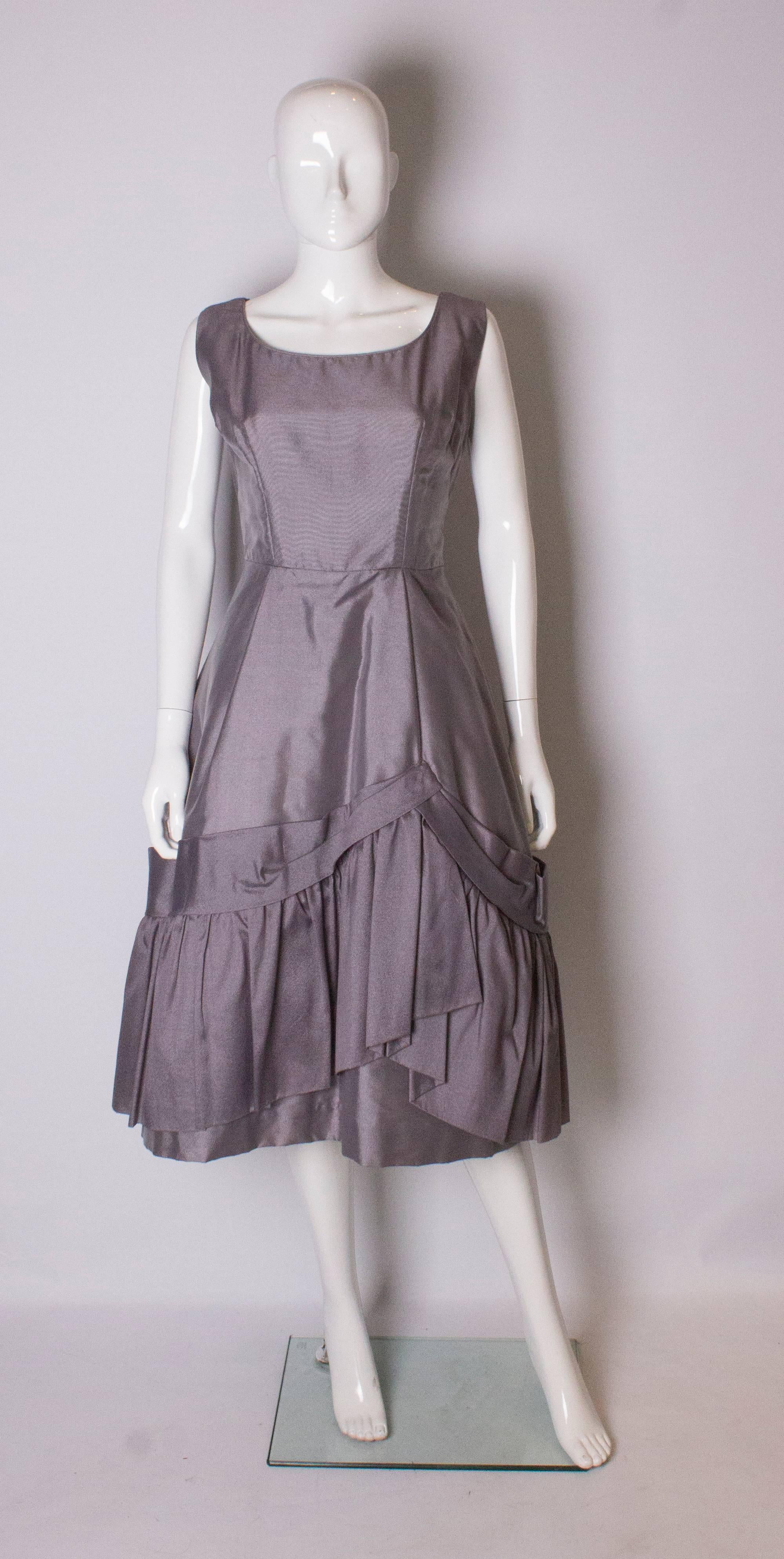 A pretty dove grey vintage cocktail dress by Zenith Original. The dress has a scoop necklline, front and back and as a built in petticoat with frill at the hem.