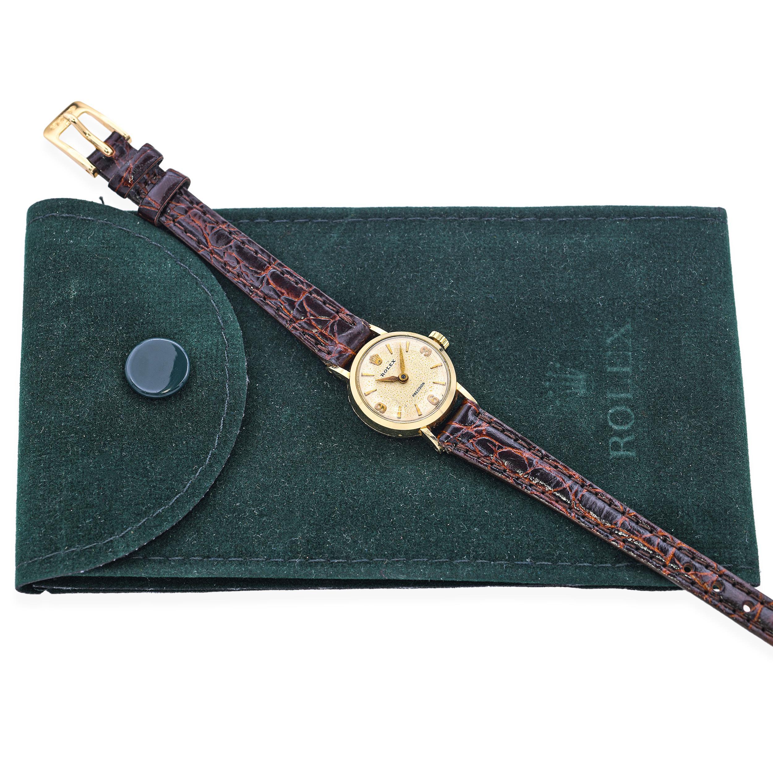 Añade un toque de elegancia vintage a tu colección con este clásico reloj de pulsera Rolex Precision 1955 para mujer. Alojada en una refinada caja de oro amarillo de 14k, esta pieza atemporal presenta un perfil redondo de 24 mm y una cálida esfera