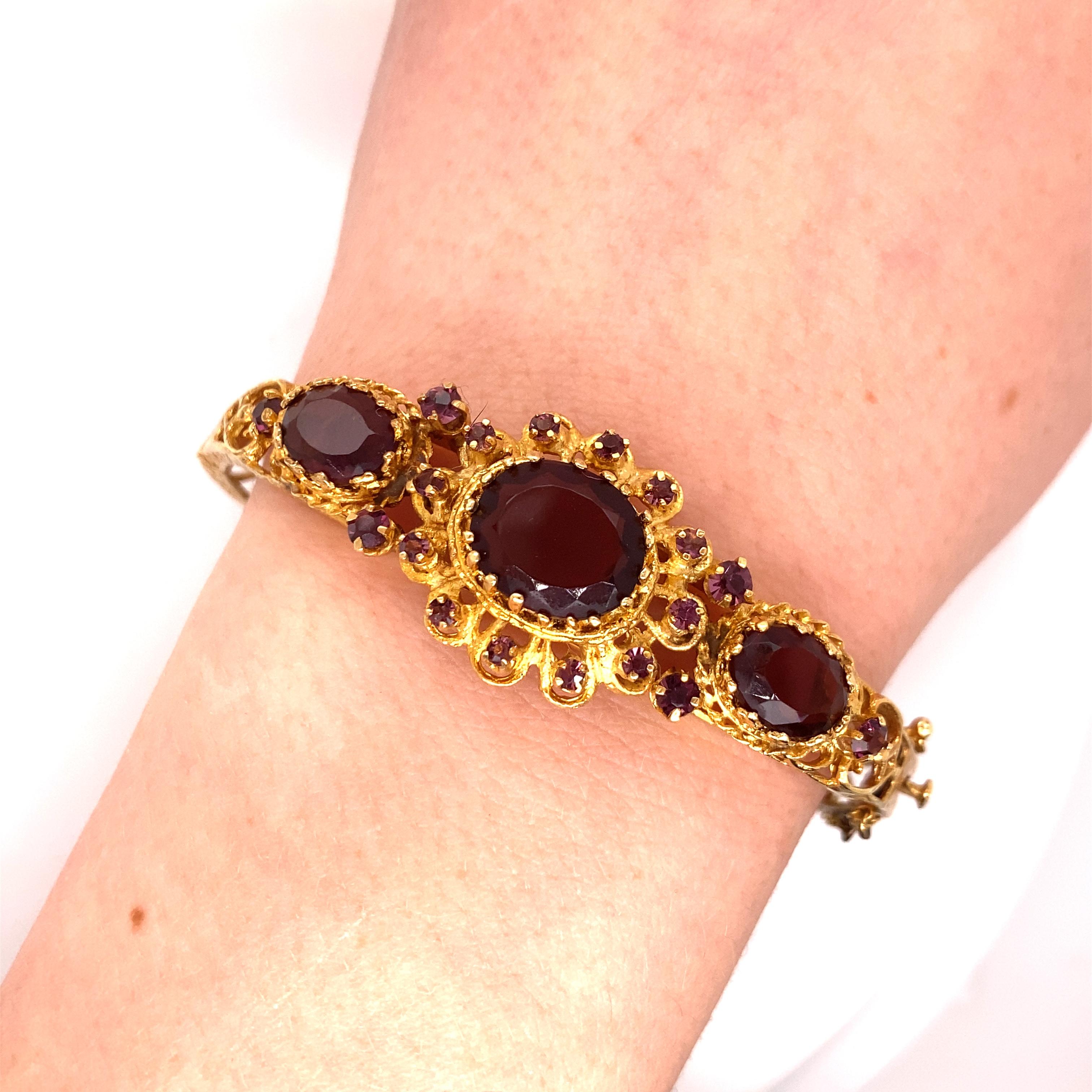 Vintage 1960's 14K Yellow Gold Bangle Bracelet with Purple Stones - The bangle's width is .75 inches. The inside diameter is 1.85 inches high by 2.50 inches wide. The bangle has engraved detail and filigree workmanship. The weight of the bracelet is