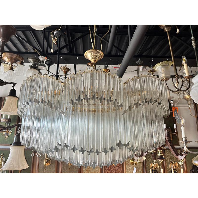 Love the scale of this rare oval Venini brass and glass chandelier with quadrilobo prisms. Original gold toned polished brass frame and finish. Stunning addition to a living room, dining room or over an island where you need something wide and