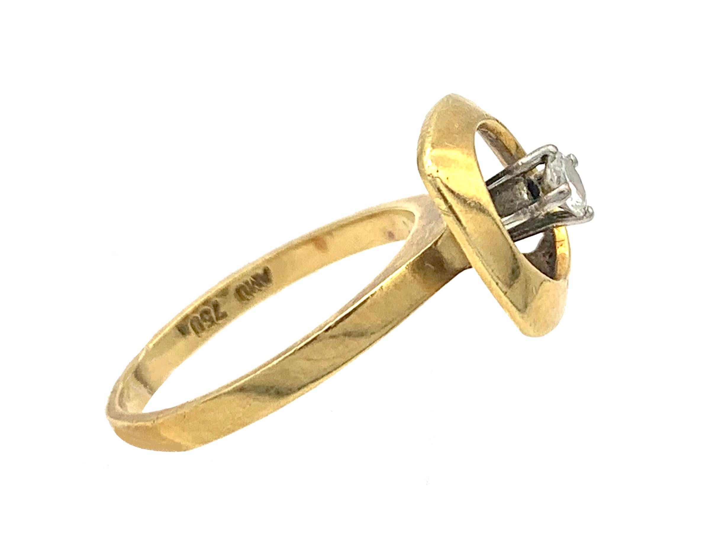 This elegant engagement ring represents the design of this swinging  decade. the round brilliant cut diamond is set in a white gold open claw setting. The ring has been made out of 18 karat yellow gold. It is marked 750.