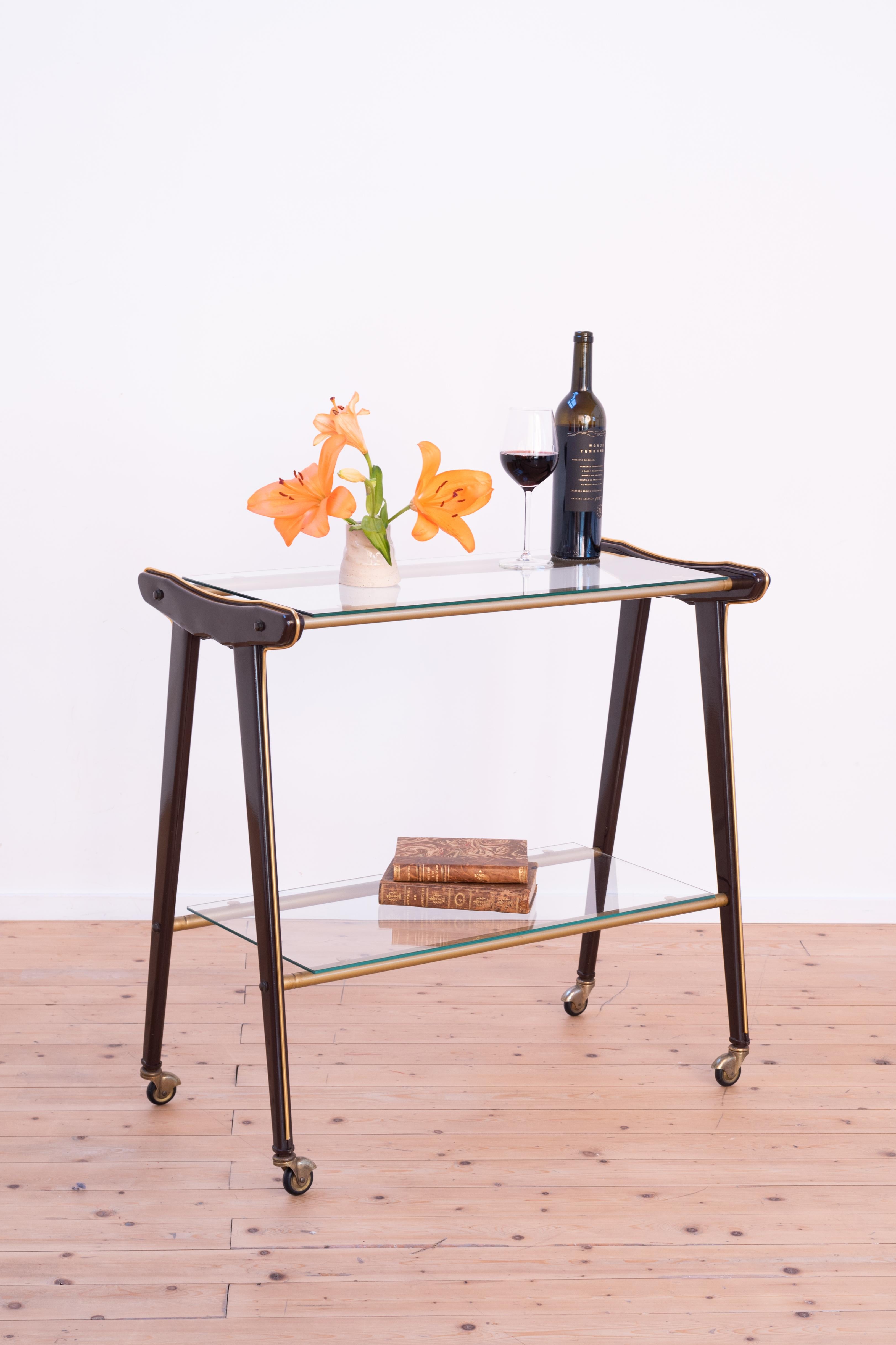 Very elegant vintage 1960s bar cart on wheels, with 2 glass shelves. 

Beautiful detail in brass on the legs of the bar cart.