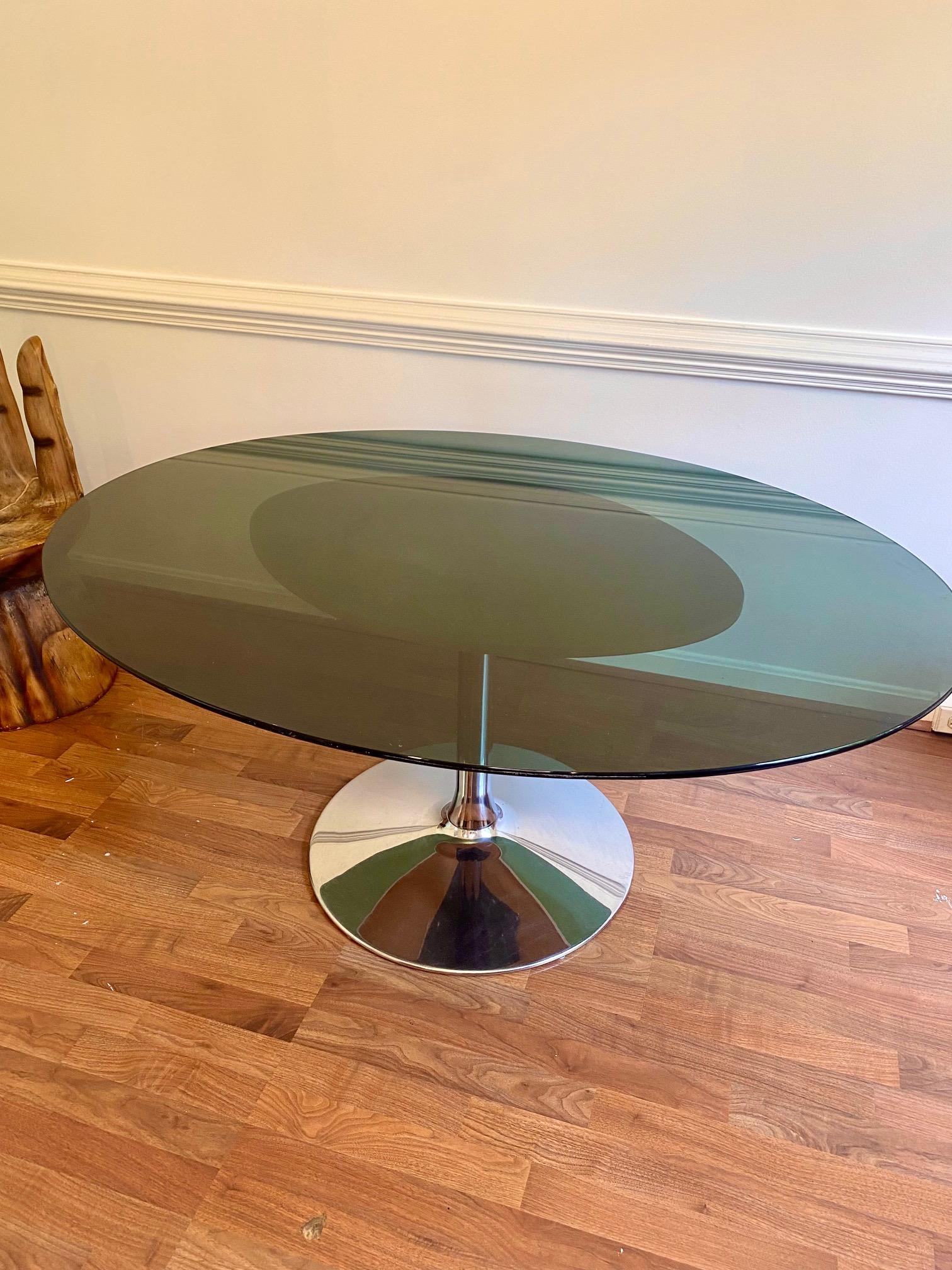 Vintage 1960s black and chrome smoked glass tulip dining table in the style of Eero Saarinen. Oval glass on top of a chrome base with white faux leather topper, which features some marks not visible when assembled. A timeless piece that will bring