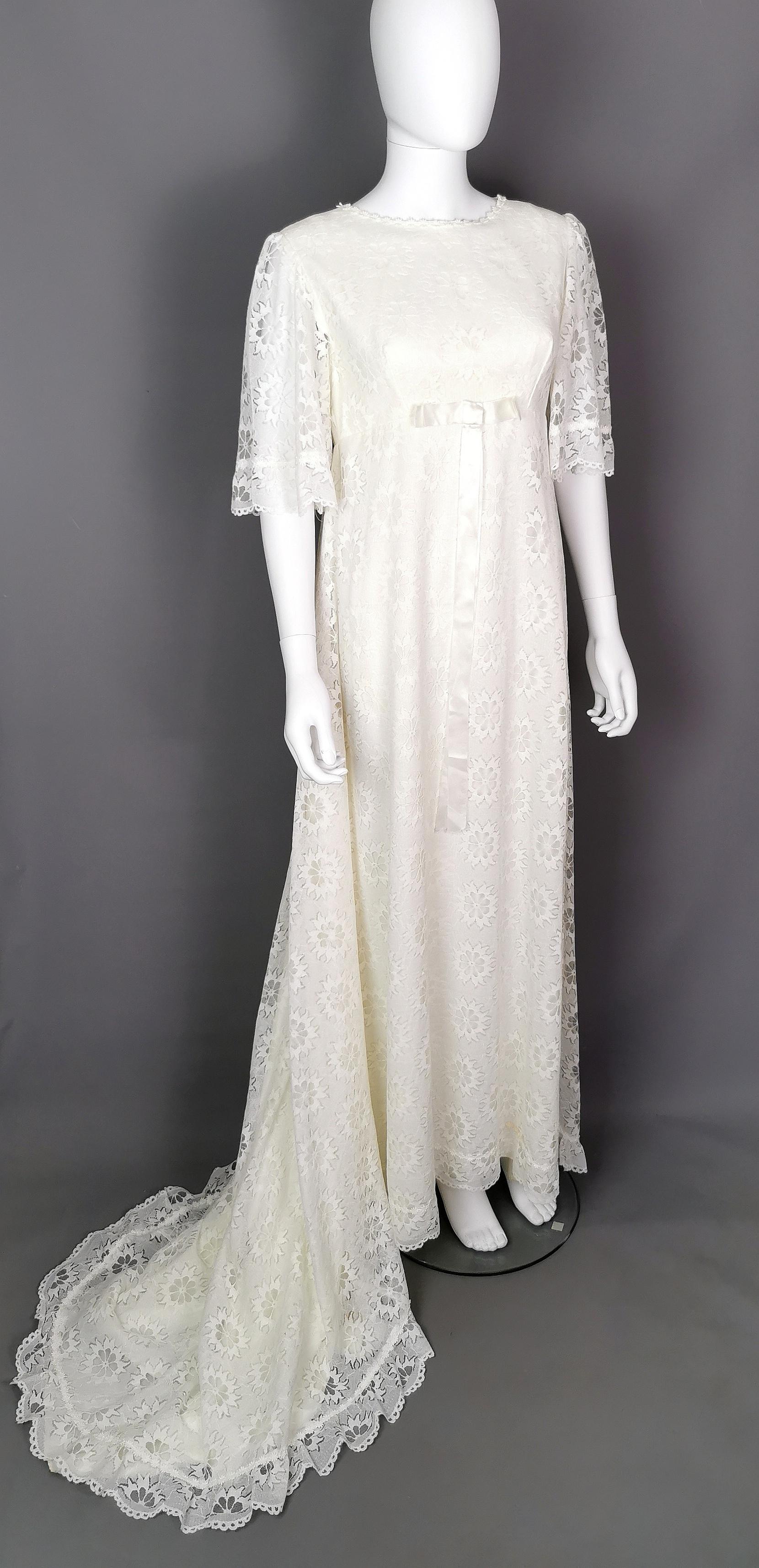 A beautiful Boho vintage wedding dress.

This wedding dress has such a pretty floaty look to it, an empire line bust leading onto the flowing skirts, the dress has a long wide train, trimmed with a ditsy floral trim and flared bell lace sleeves.

A