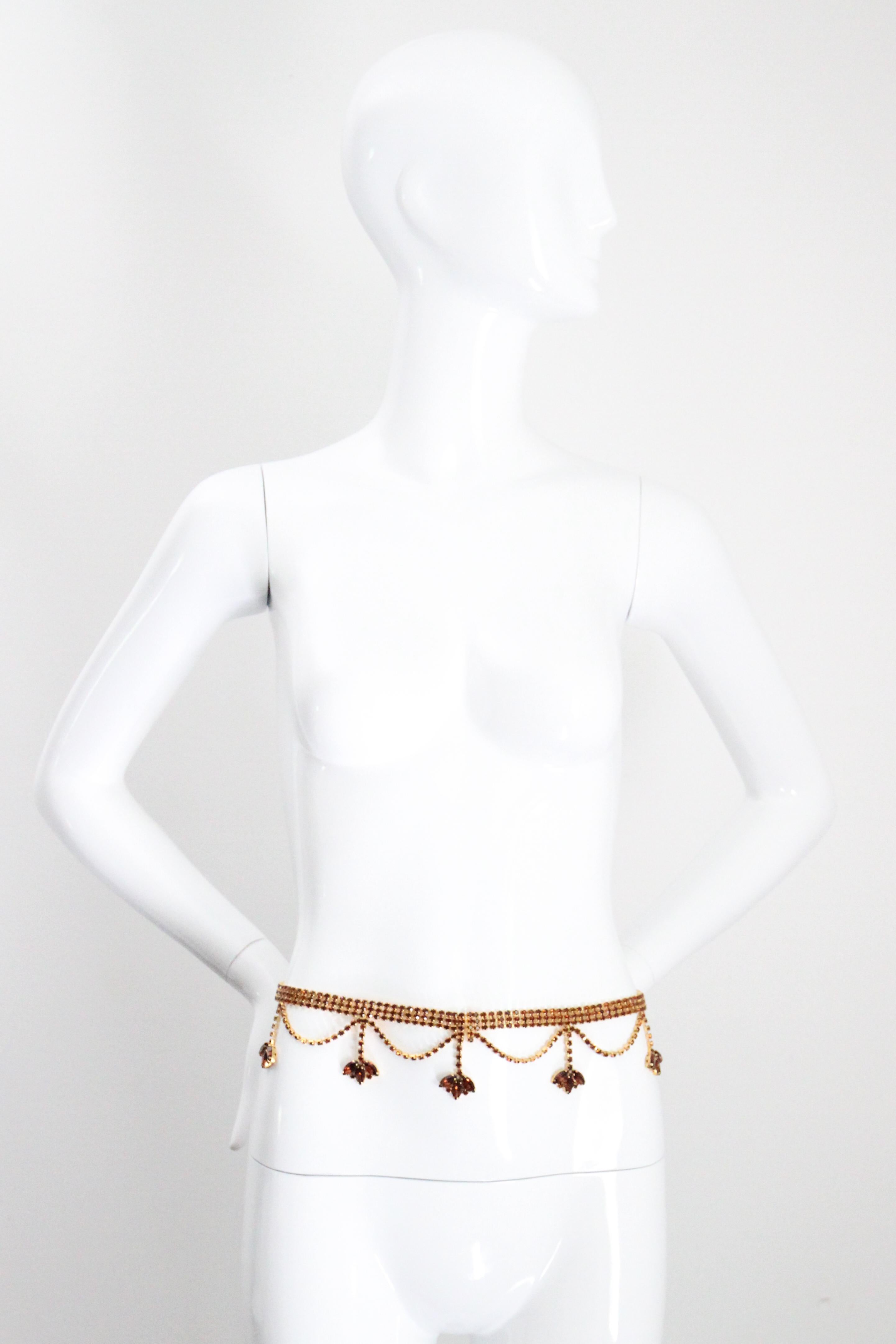 This truly spectacular 1960's statement belt, composed of bronze coloured glass rhinestones, in gold toned metal settings is the perfect statement piece to your outfit. The triple inlaid rhinestone chain base, draws together centrally along the