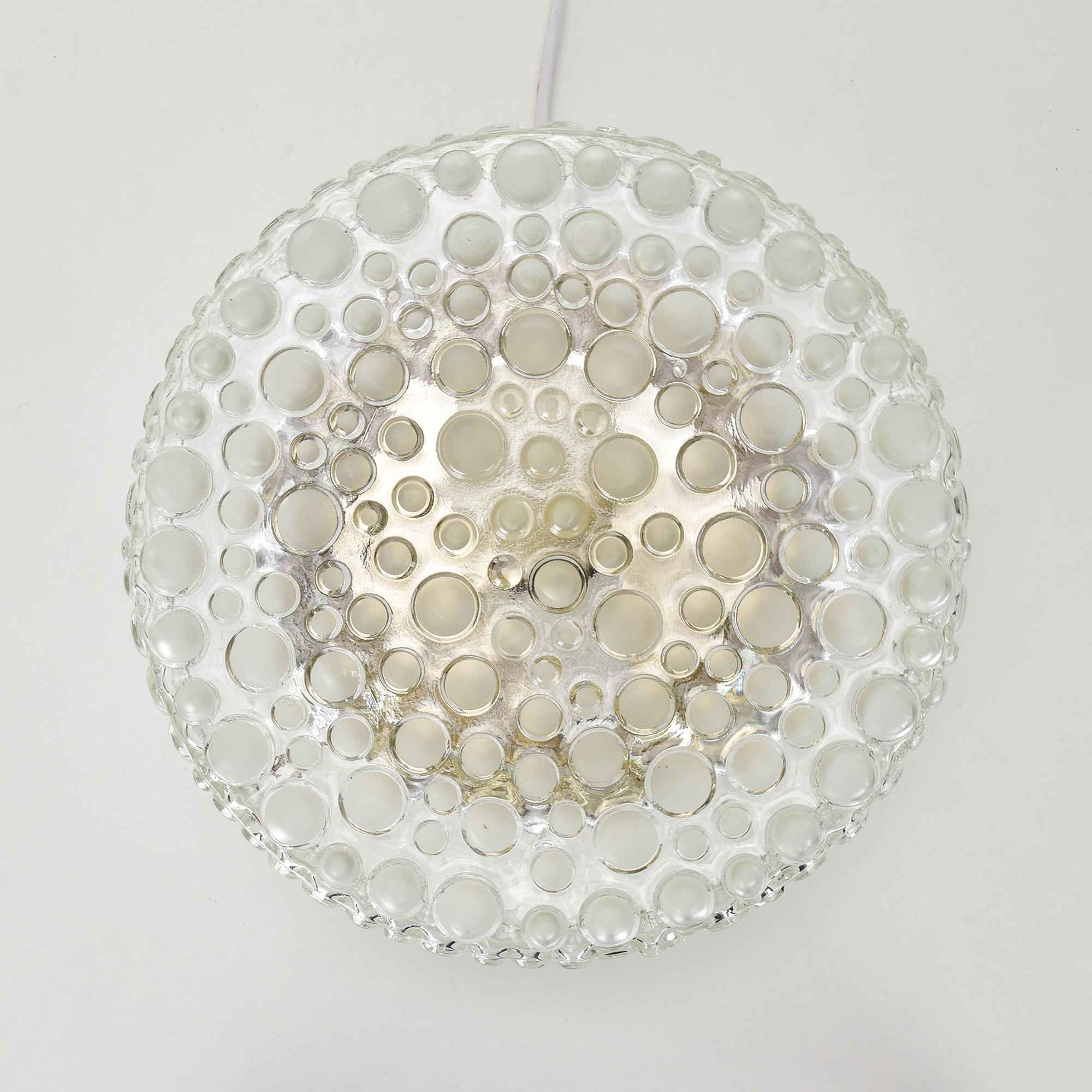 This Mid-Century bubble glass wall lamp or ceiling light flush mount, designed by Hustadt in the 1960s in Germany, brings a unique and retro aesthetic to any space. The circular glass design features a captivating bubble pattern, creating a stunning