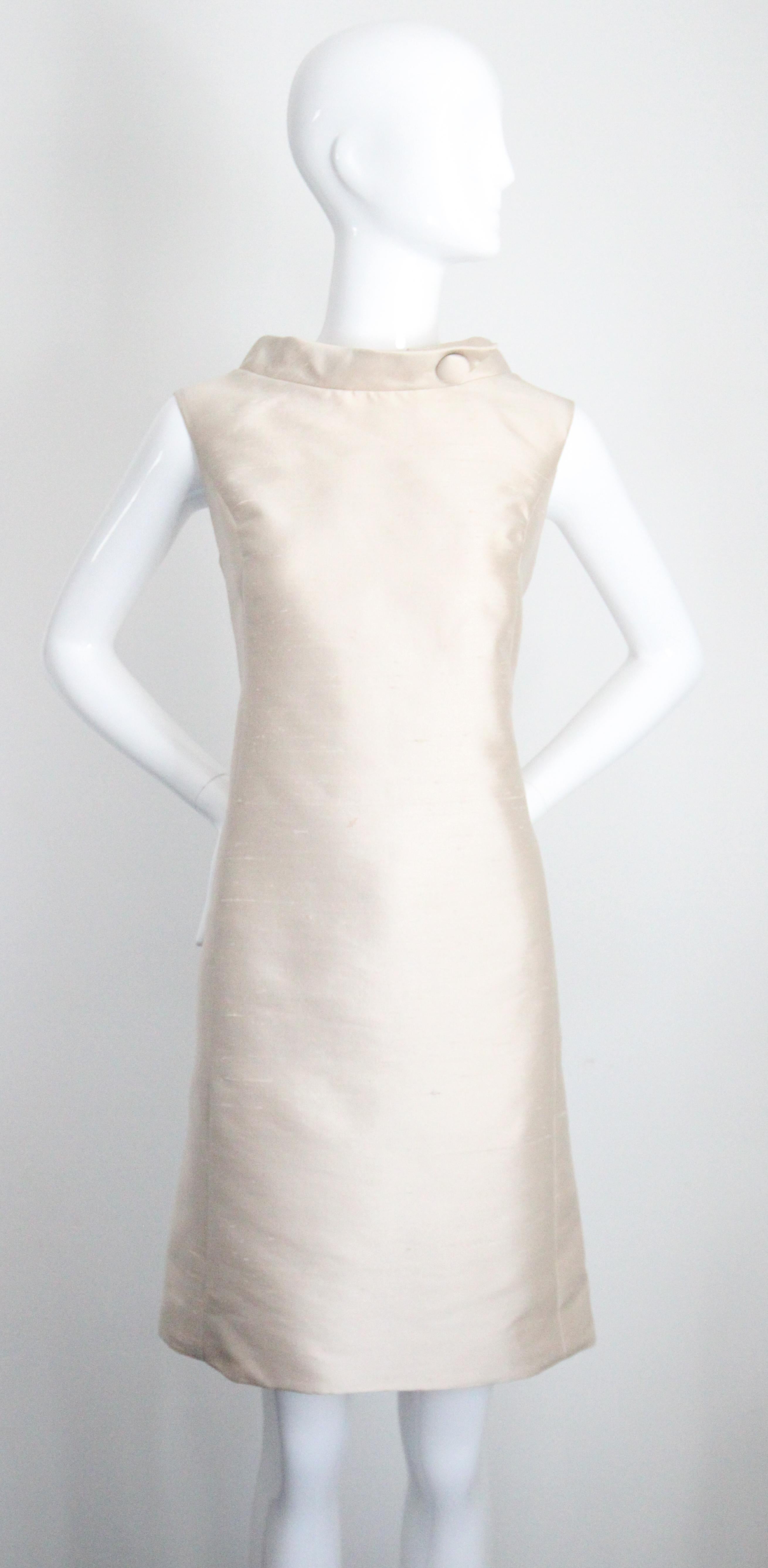 Cet ensemble majestueux de robe en soie champagne des années 1960 et de manteau assorti, rehaussé de bordures en vison blond, est parfait pour une occasion spéciale. 

L'élégante encolure est rehaussée d'un col mandarin qui est décoré d'un bouton