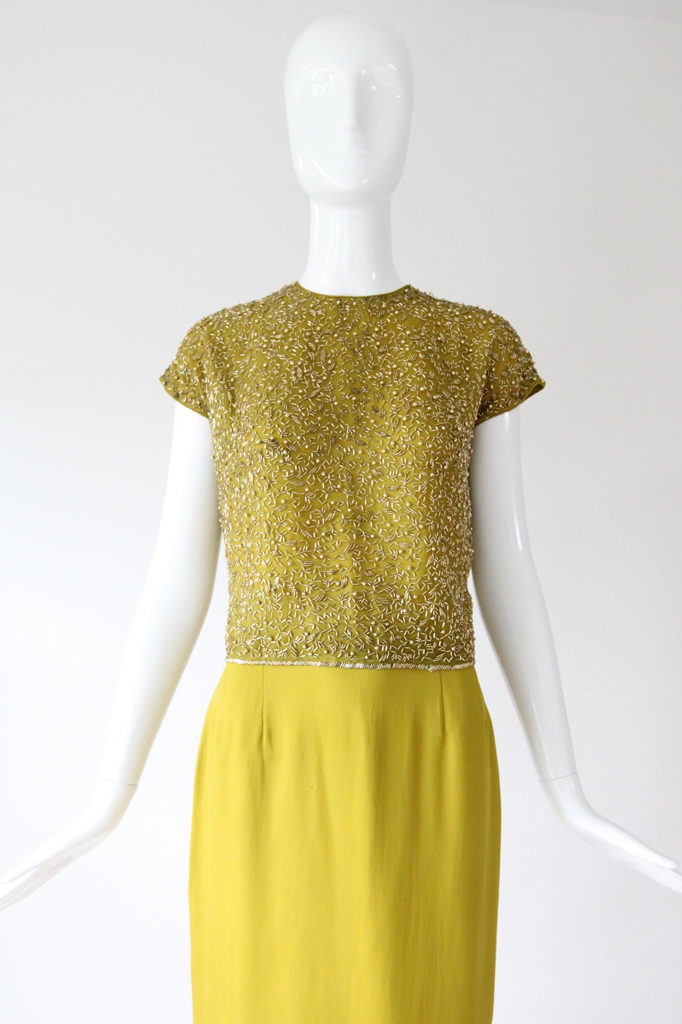 Dieser originelle Cocktailanzug aus den 1960er Jahren ist eine Vision aus chartreusegrünem Seidenchiffon, der mit goldenen Glasperlen und runden Goldperlen verziert ist. Er ist genau das richtige Stück für Ihre Sammlung. 

Der Rundhalsausschnitt der