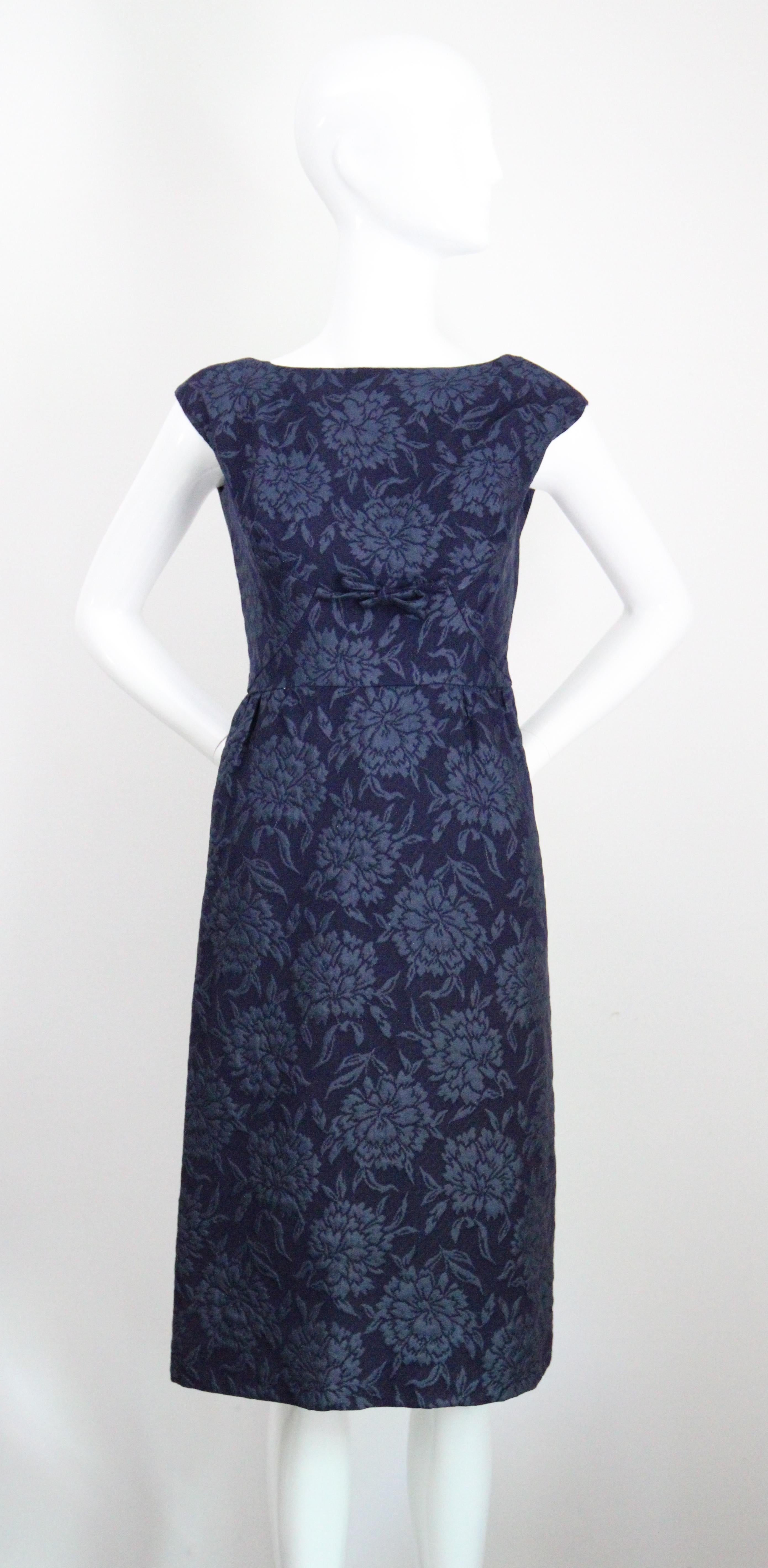 Rendered in the most elegant shade of navy and French blue silk and wool floral brocade, this original 1960's vintage Christian Dior dress and matching jacket ensemble is a rare addition to your vintage collection.

The bateau cut neckline of the