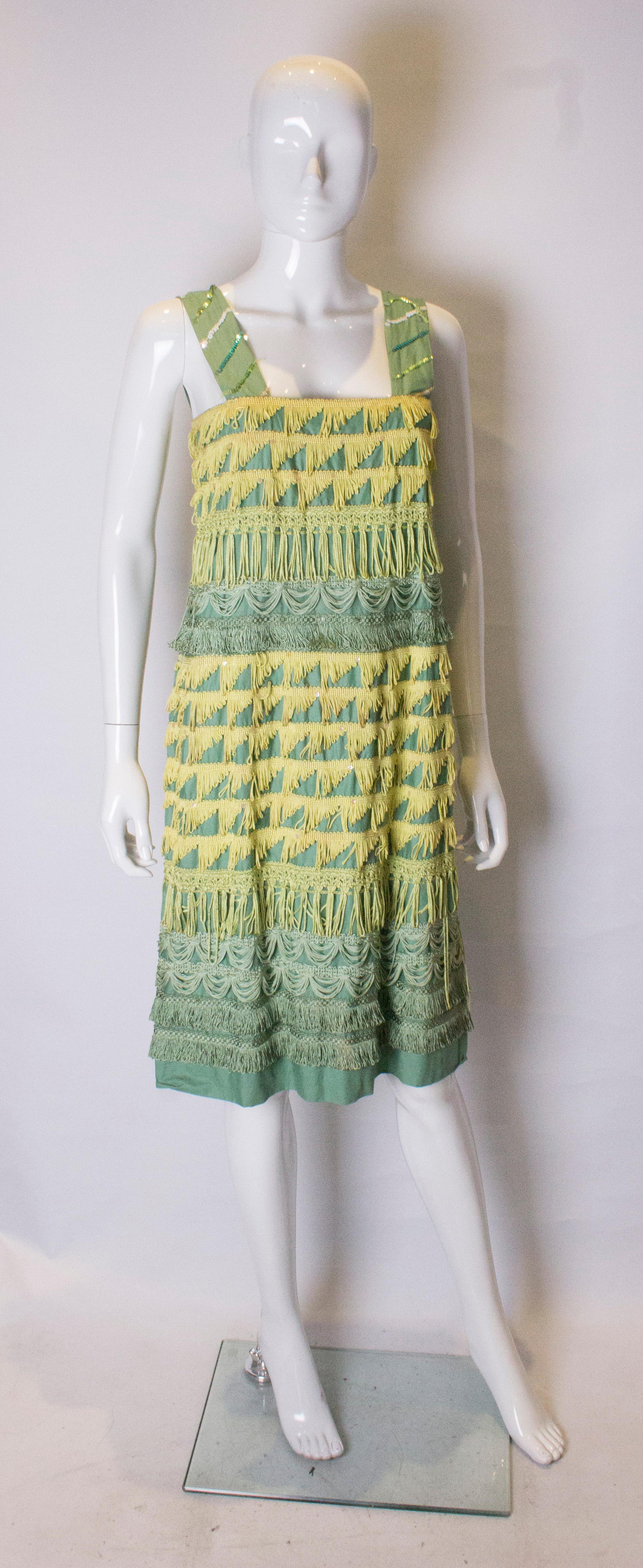 A chic cocktail dress for Spring.In wonderful shades of yellow and green with fringe detail. The dress has wide shoulder straps with sequin detail and a central back zip.