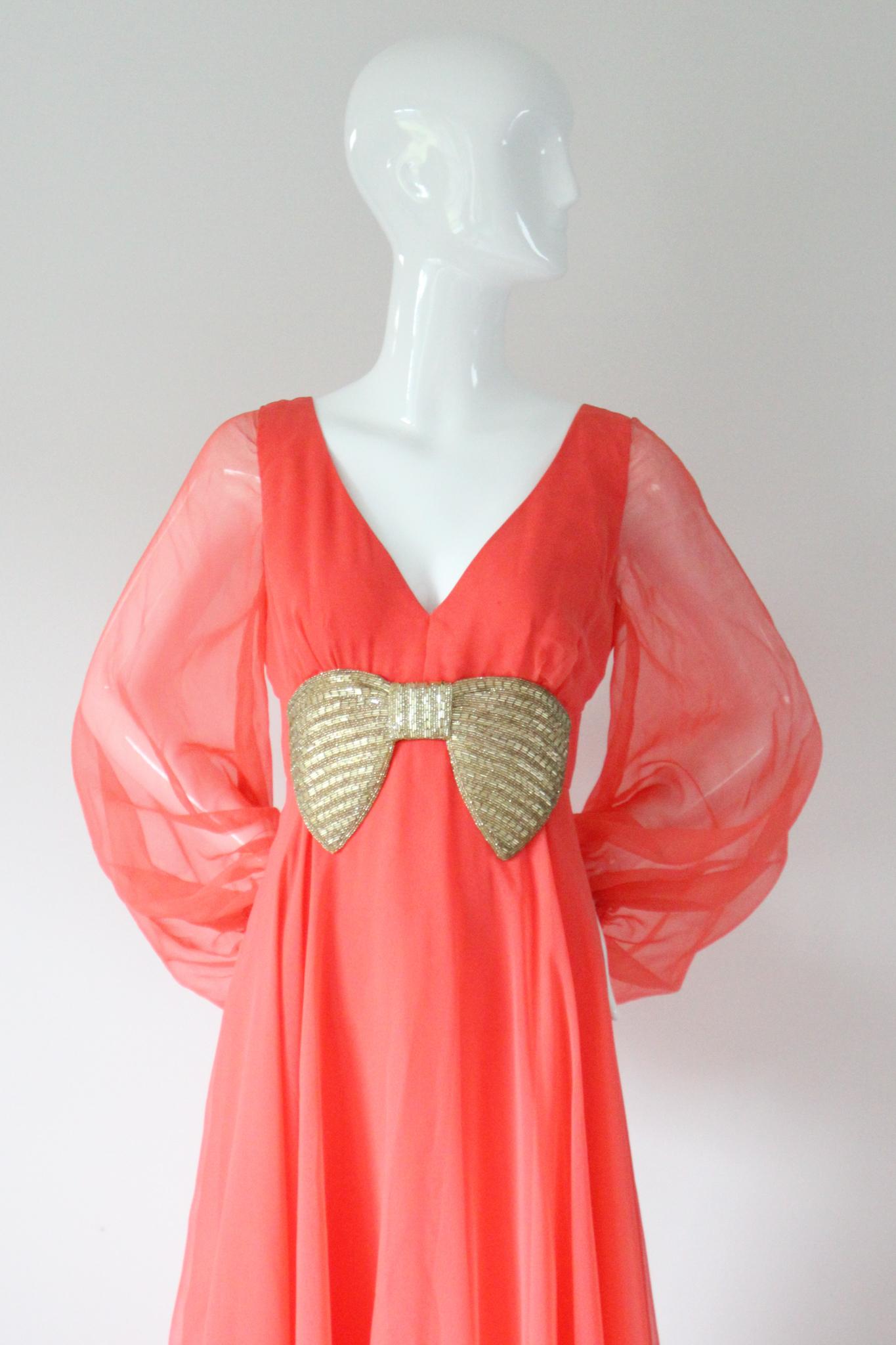 Dieses originelle Kleid aus den 1960er Jahren ist in einem auffälligen und leuchtenden Korallenchiffon gehalten und mit einer perlenbesetzten Schleifenapplikation in Silber verziert. Es ist genau das richtige Stück für Ihre lebendige