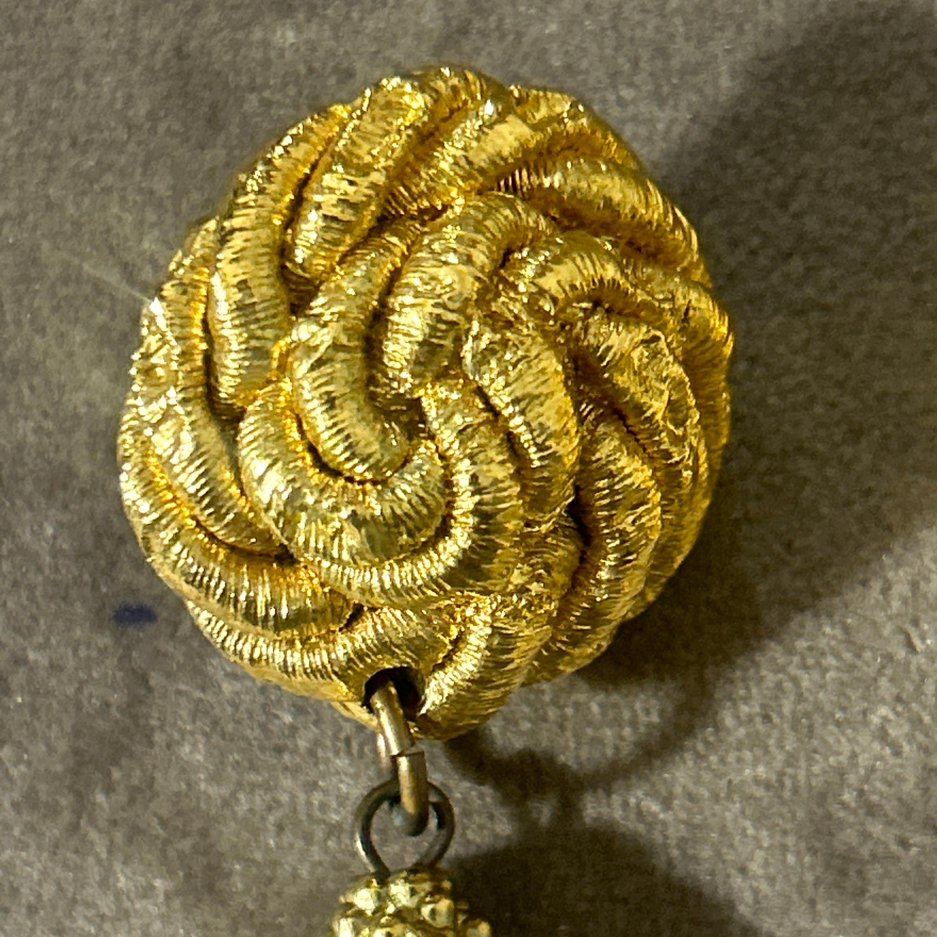 This stunning pair of vintage earrings from the 1960s exudes opulence and bold sophistication. Crafted with intricate detail, the earrings feature a circular, textured top with a knotted design, resembling a twisted rope motif, which adds depth and