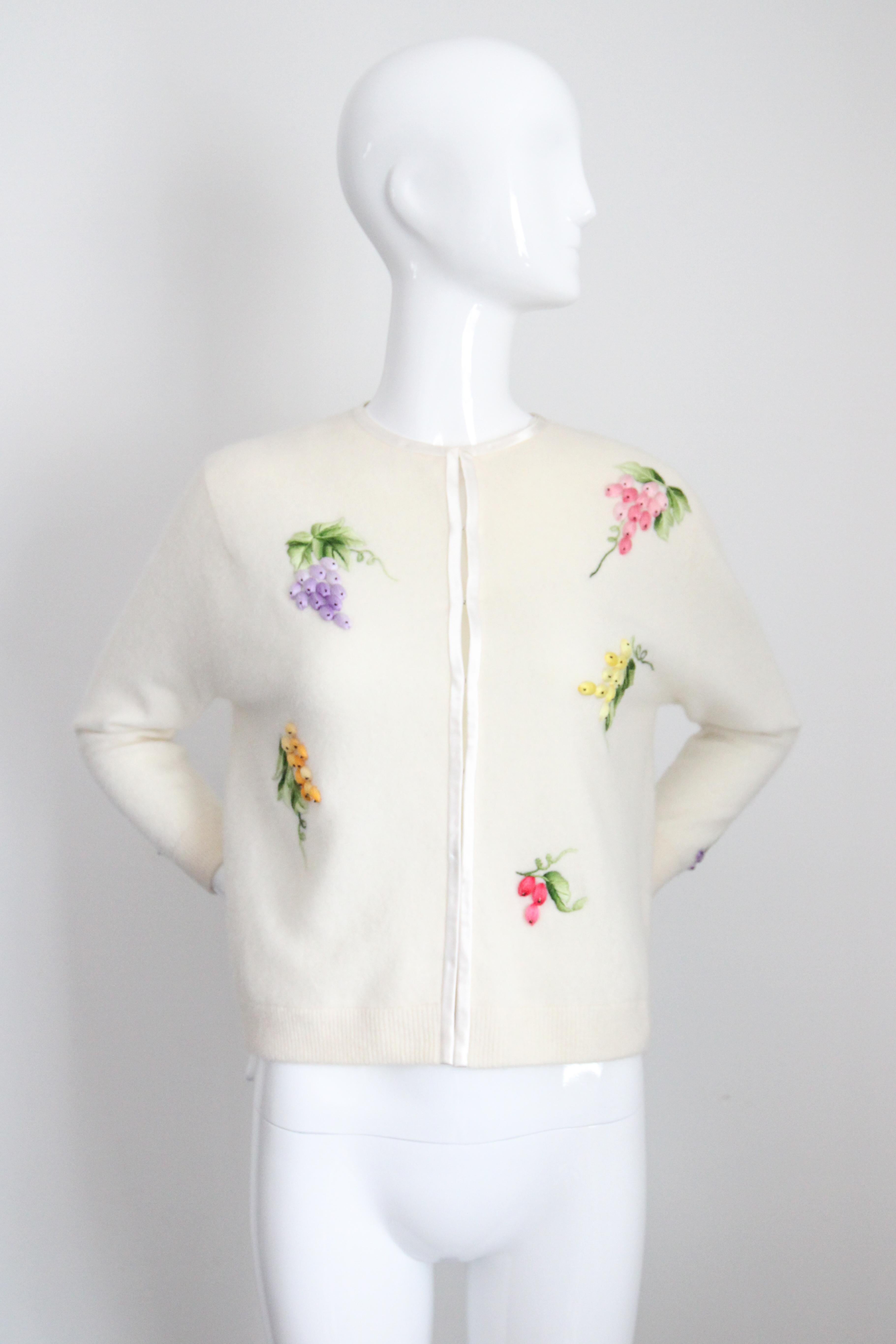 This delightful 1960's cream lambswool and angora cardigan, embellished with raised embroidered bunches of grapes, in shades of yellow, pink, and purple, surrounded my decorative embroidered vine leaves, is just the piece for your seasonal
