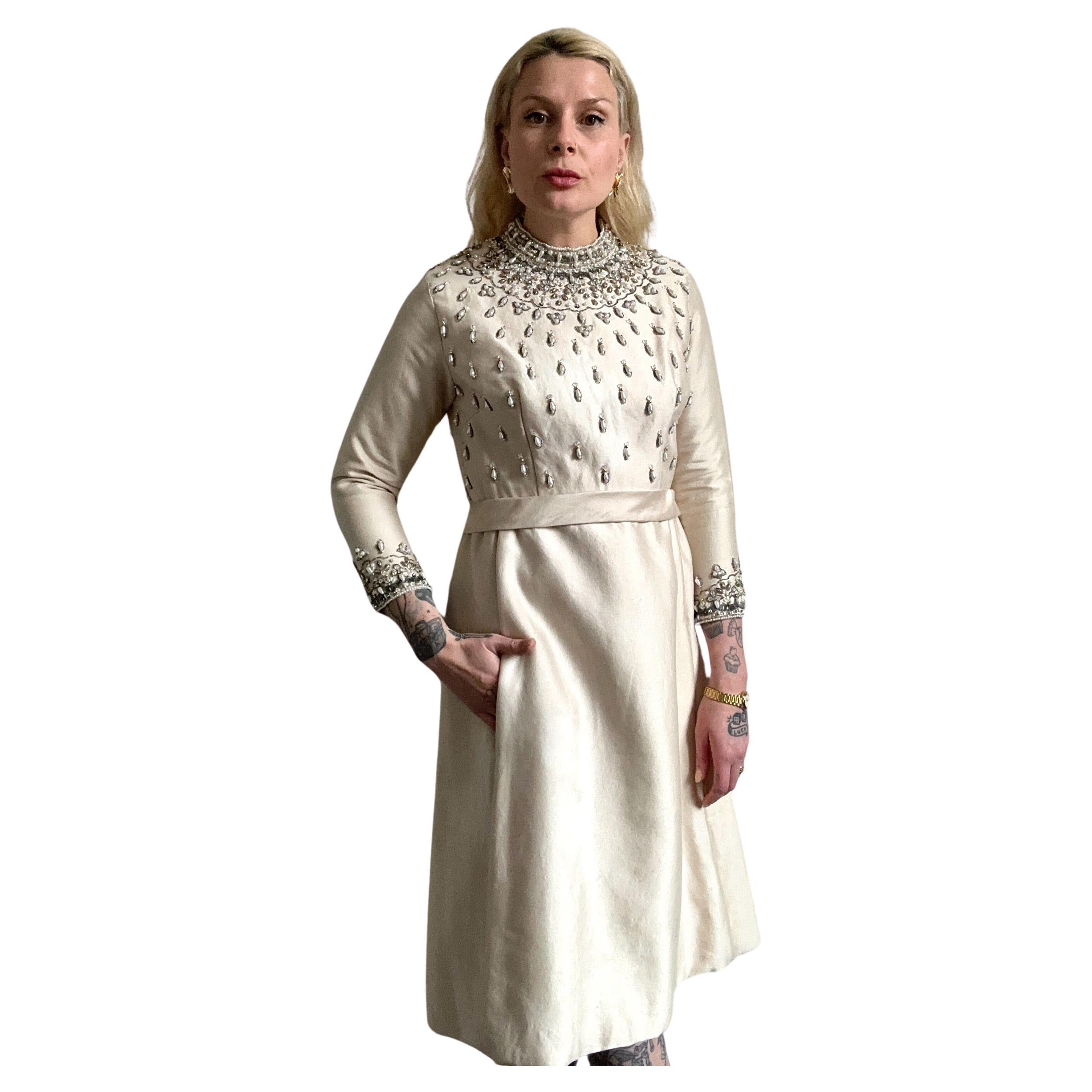 A vision rendered in a truly embellished fashion, this original vintage 1960's cream wool silk dress, embellished with silver glass beads, pearlescent beads, gold beads and silver claw set rhinestones, showcases the incredible design and