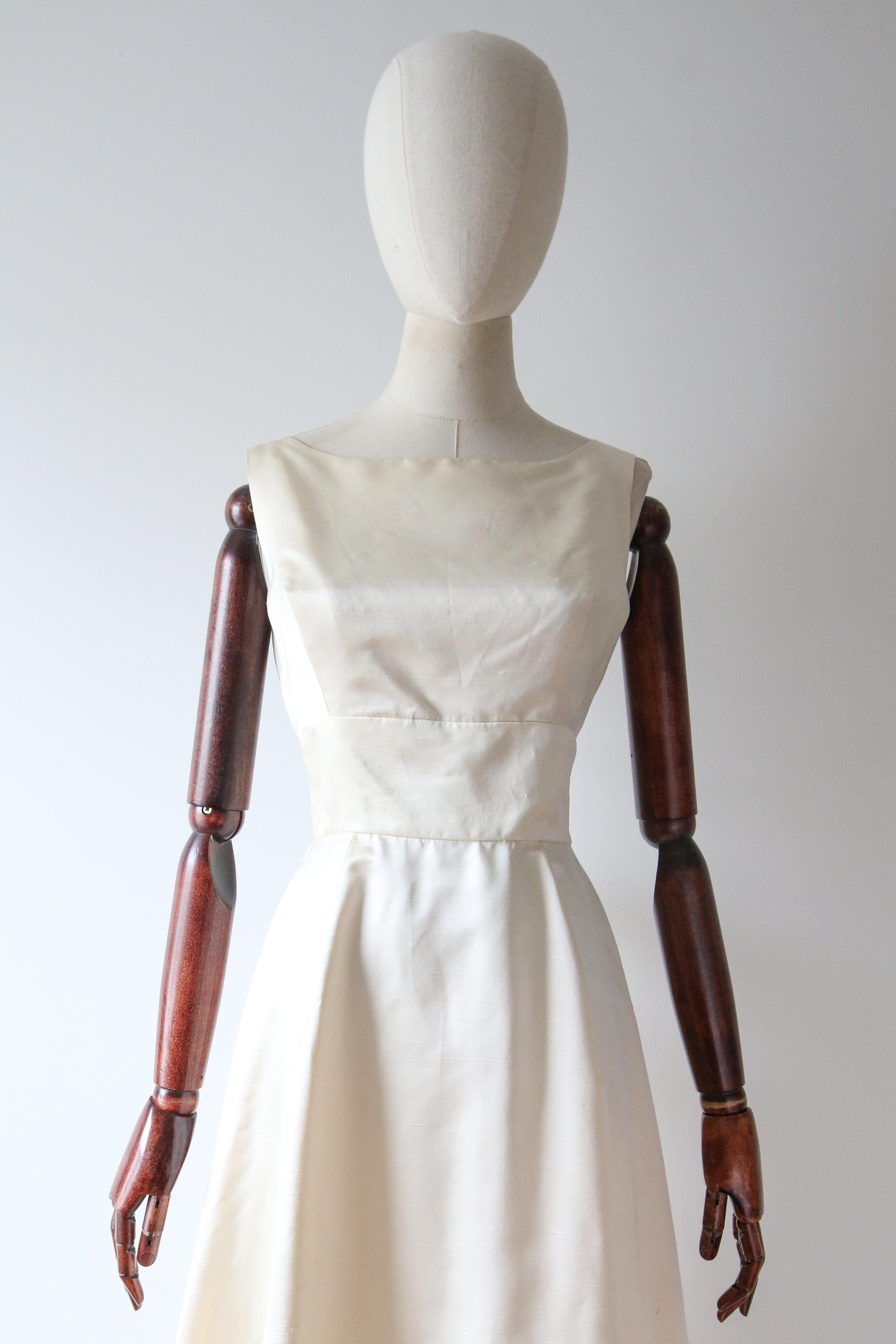 Este atemporal y elegante vestido de seda color crema de los años 60, con un diseño icónico, será sin duda uno de los favoritos de tu colección vintage. 

El suave escote barco está enmarcado por tirantes de anchura media, que realzan el corte sin