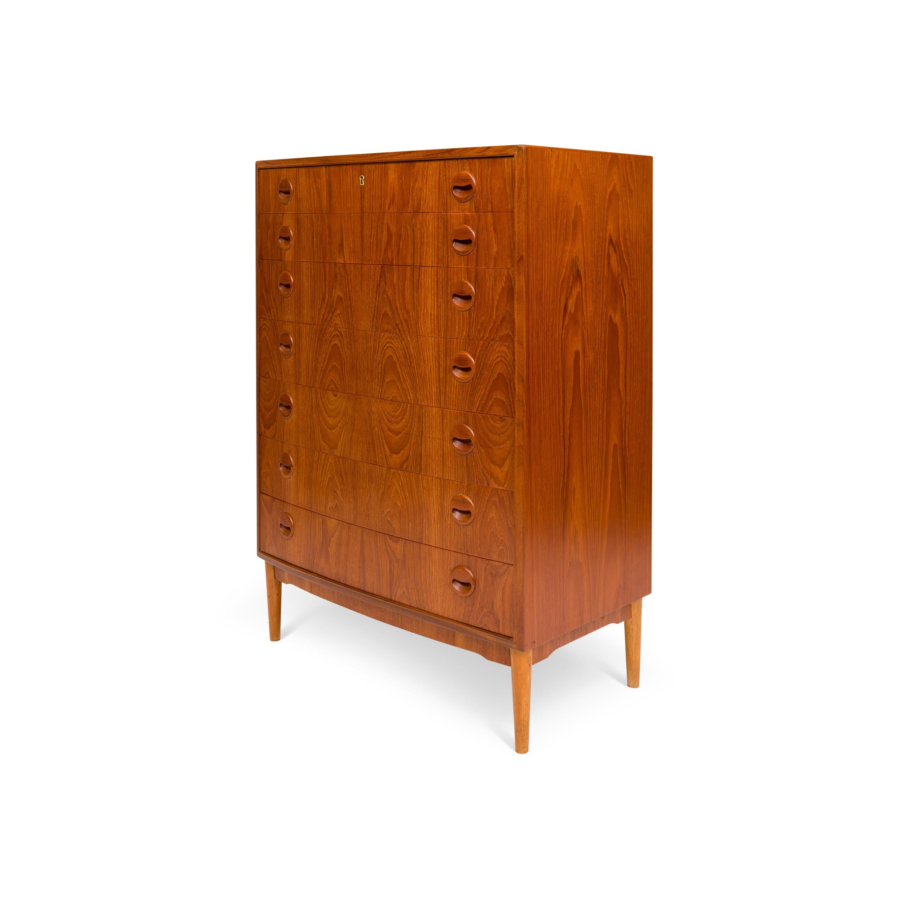 This Danish tallboy chest of drawers embodies the essence of Mid-Century design. Its seven drawers, adorned with sculptured wooden handles and seamless dovetail joins, effortlessly combine functionality with elegance. The natural teak grain adorns