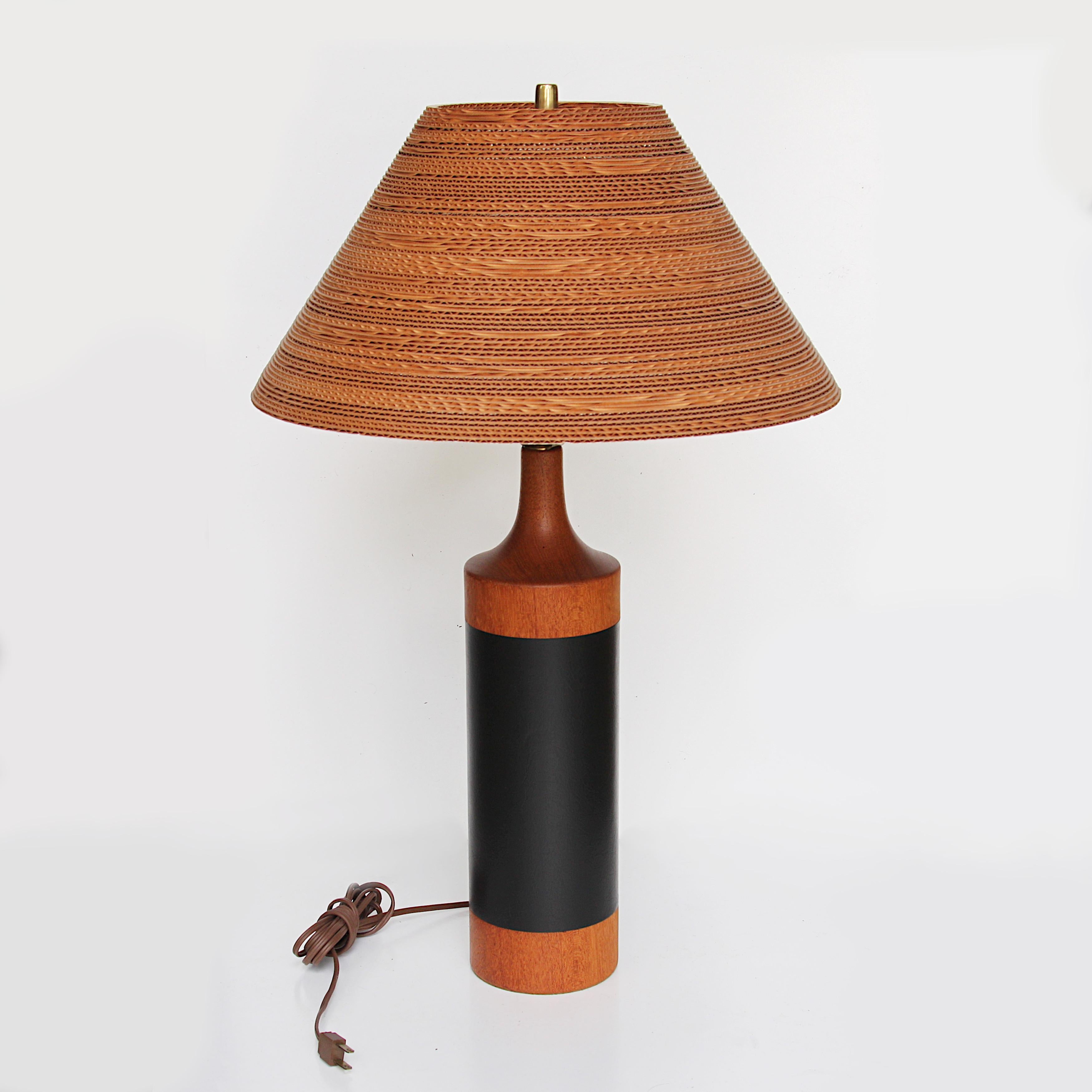 Unique 1960's Danish Modern table lamp. Lamp features a solid teak body with black, inset leather-wrap. The shade is a period, corrugated cardboard shade that complements the lamp beautifully (16.5