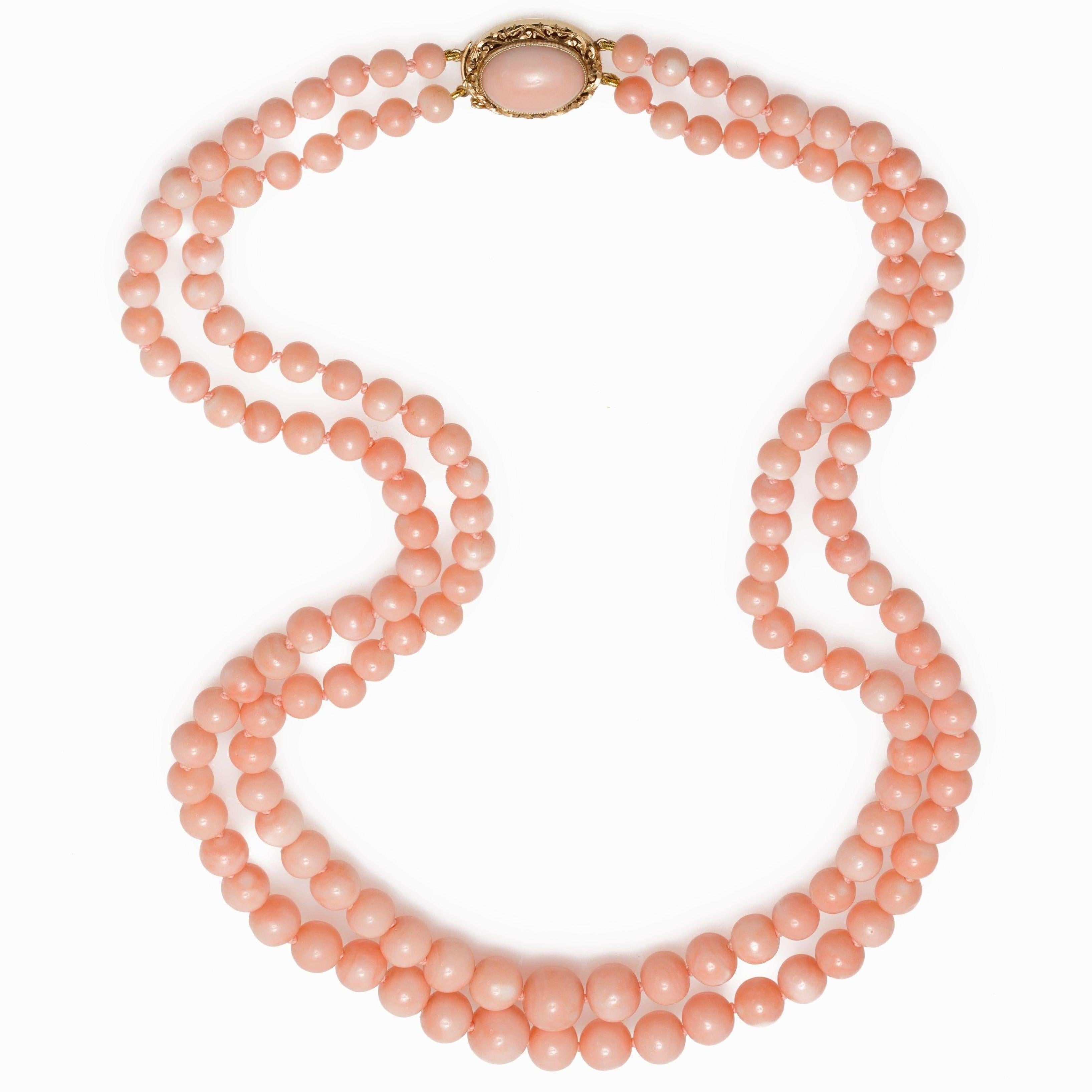 A vintage double strand Angel Skin Coral necklace circa 1960, with oval medallion in 18K yellow gold clasp. Crafted during the mid-century period, this double strand beaded necklace features original Angel Skin Corals of very high quality and very