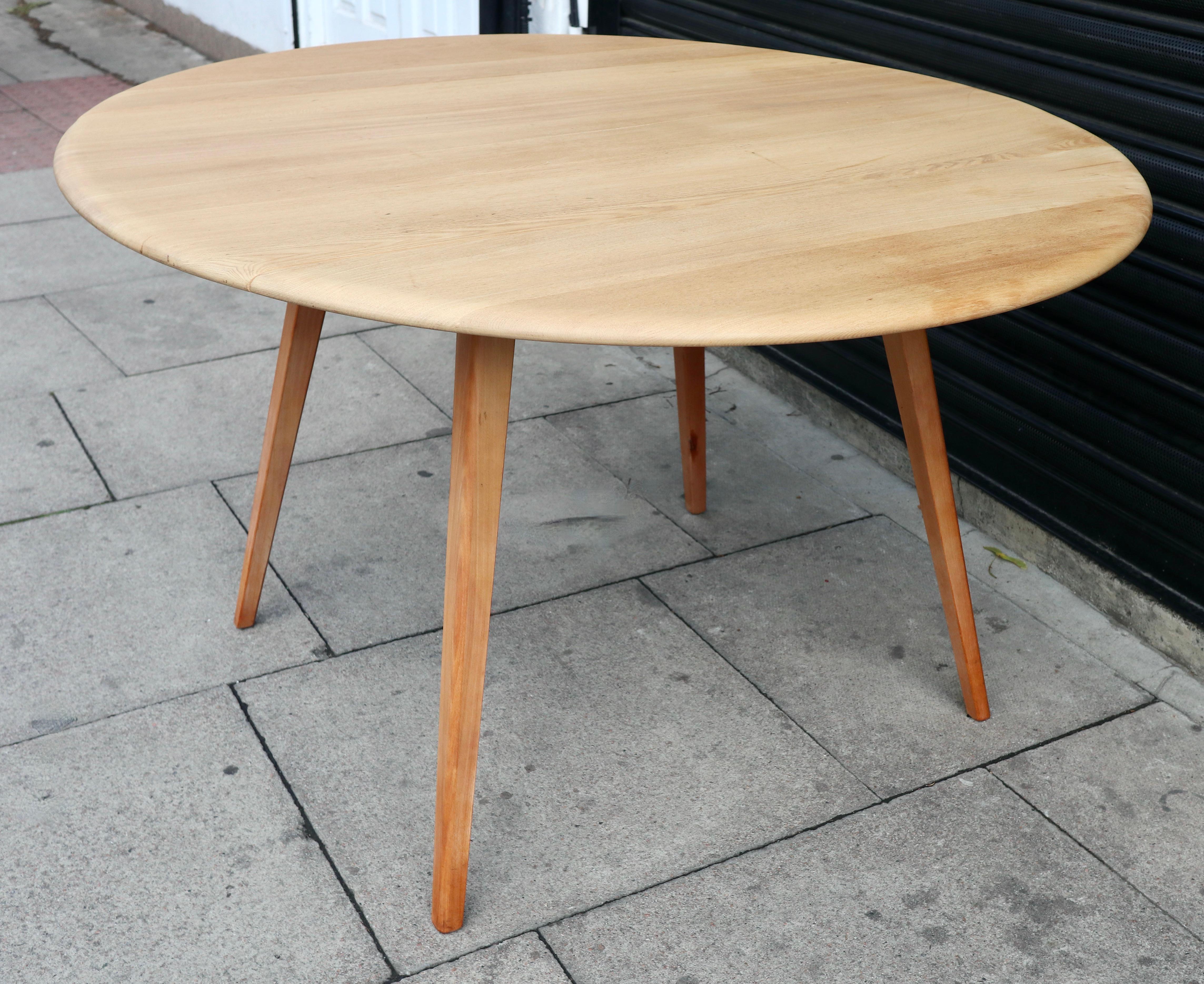 A vintage 1960s drop leaf ercol round/oval dining table.  This table has a solid Elmwood top and a four legged solid Beech base. It has two drop leaves and is very good vintage condition, having been completely refurbished and refinished.