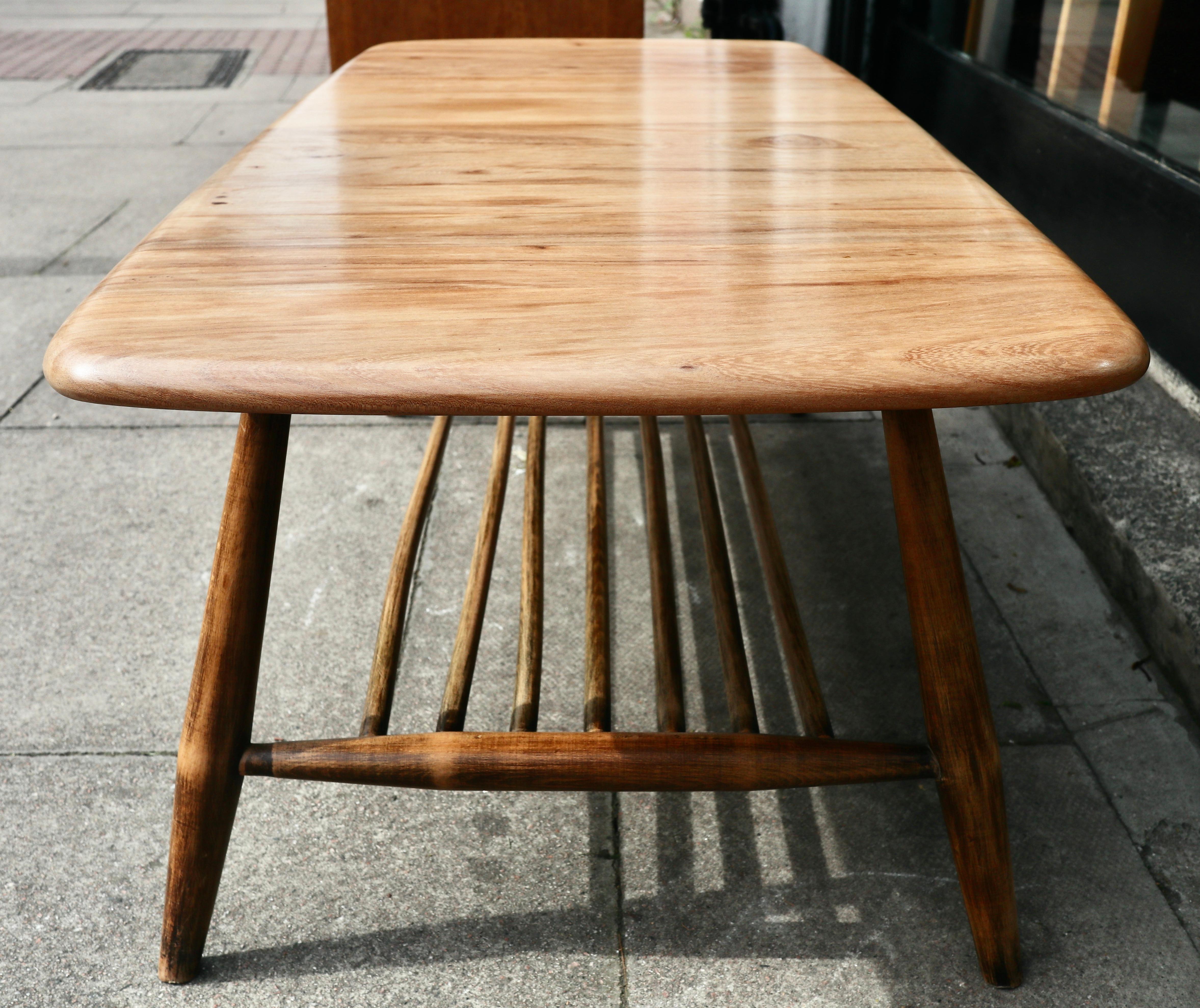 Vintage 1960s Ercol coffee table with magazine rack. This table has a, particularly figured and beautiful, solid elm top and solid stained beech base. It is in very good vintage condition with the top having been stripped of it's stain, varnished