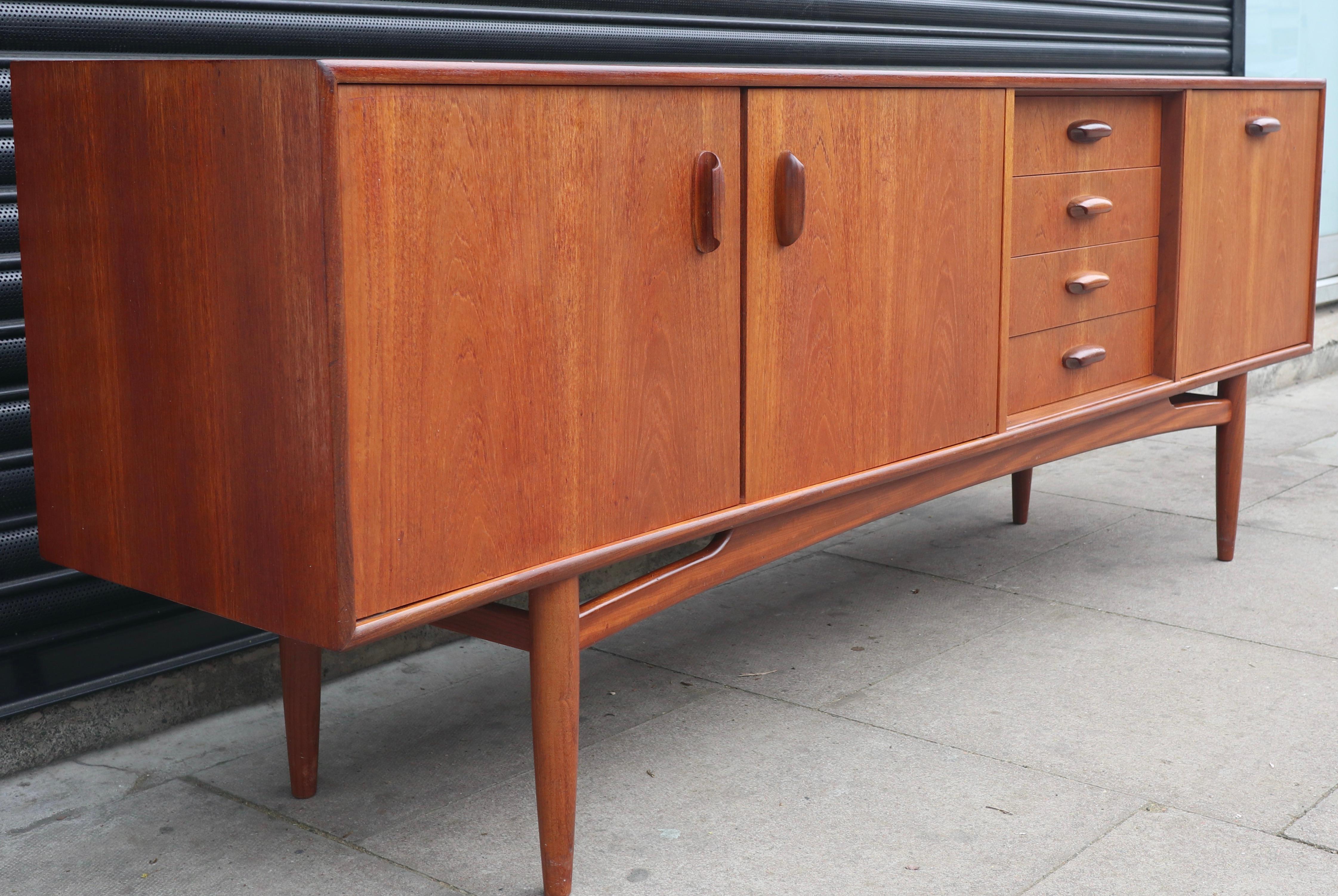 
This piece shows its quality with sculpted handles, beautiful dovetail joints and warm grades of golden Teak.
It also holds generous storage with 4 well-proportioned drawers, a double opening cupboard with a fixed shelf and a drop down