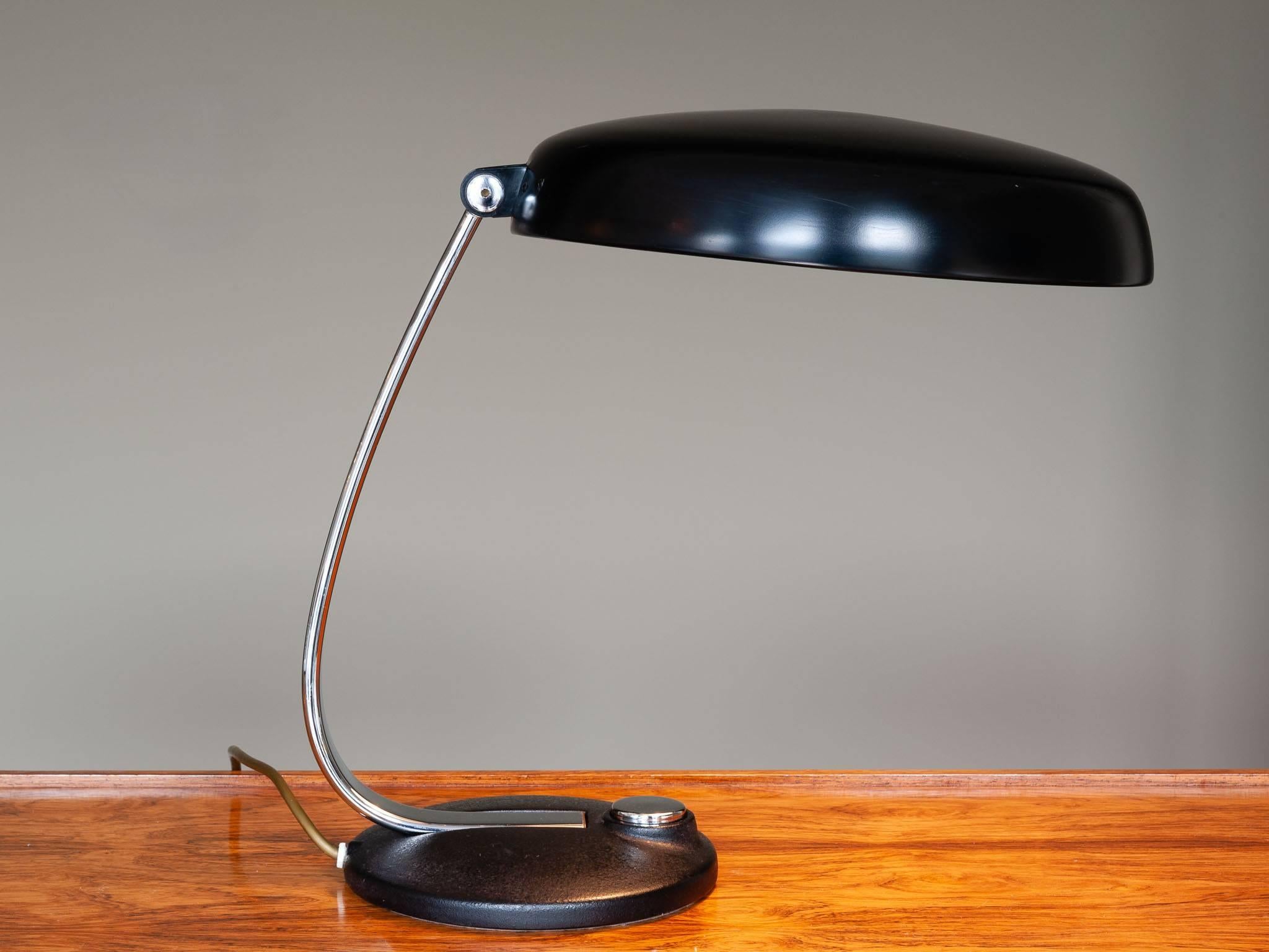 1960s German Kaiser style desk lamp with a polished black canopy shade with white interior which contrasts with the black matte enameled base. The polished chrome adjustable stem and large on/off button contrast perfectly against the rest of the