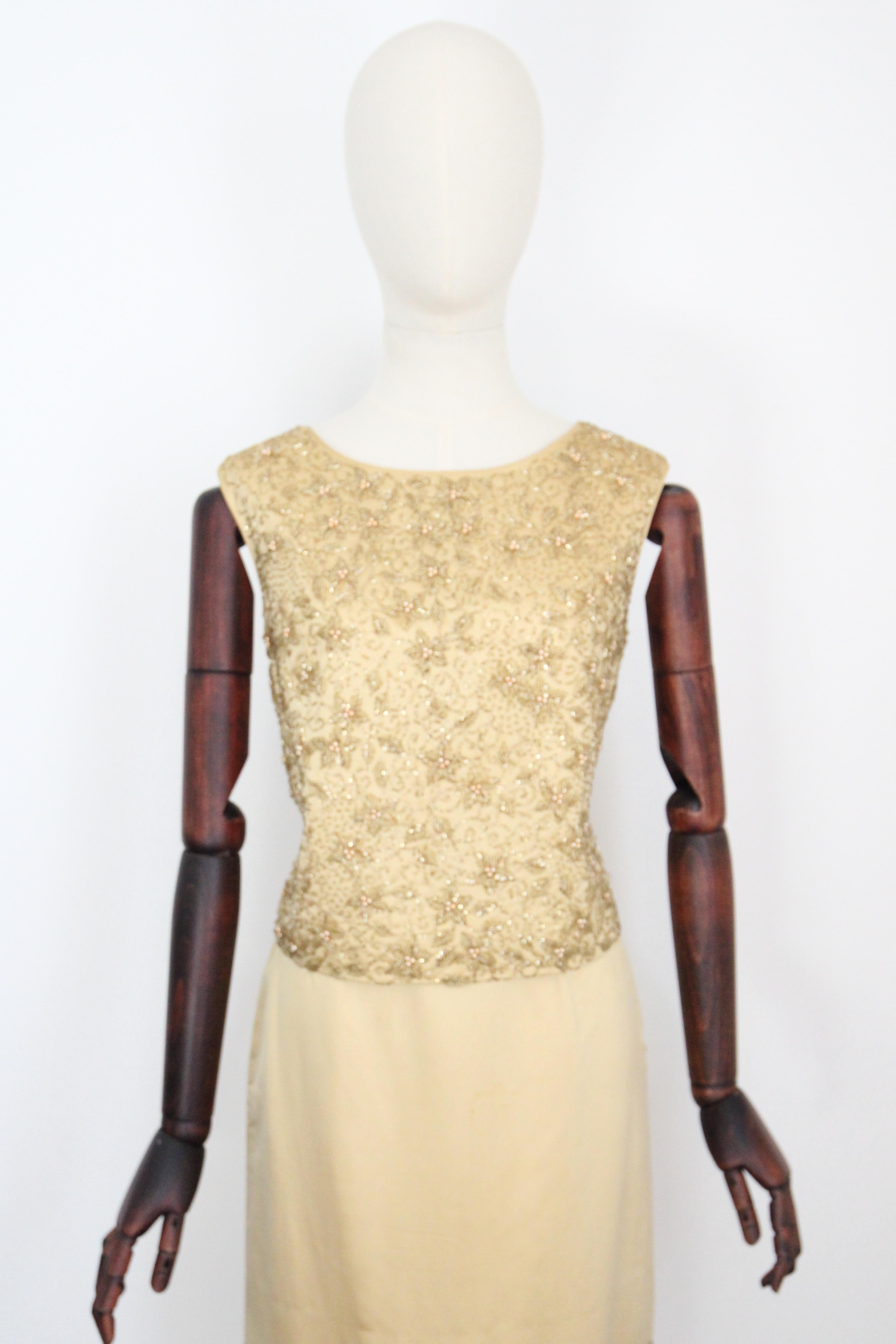 A vision in gold! This original 1960's vintage cocktail suit, rendered in a lustrous gold satin and embellished with a gold glass floral beadwork, is just the perfect addition to your seasonal wardrobe. 

The rounded neckline of the blouse, is