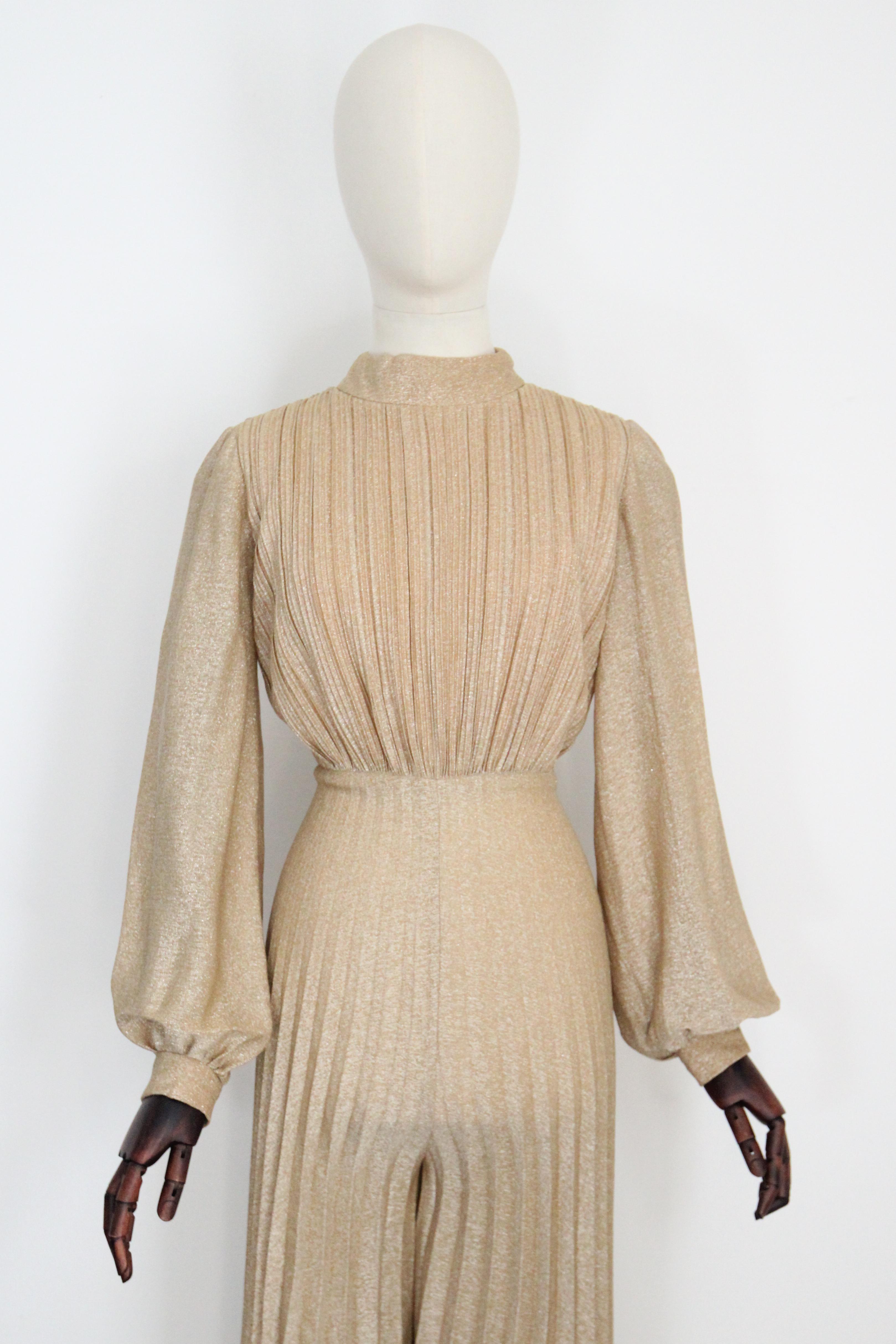 An iconic piece to behold, this original 1960's gold lurex accordion pleated palazzo jumpsuit, is just the statement piece for your cocktail wardrobe. 

The rounded high neckline is framed by a raised collar detail, which draws together along the