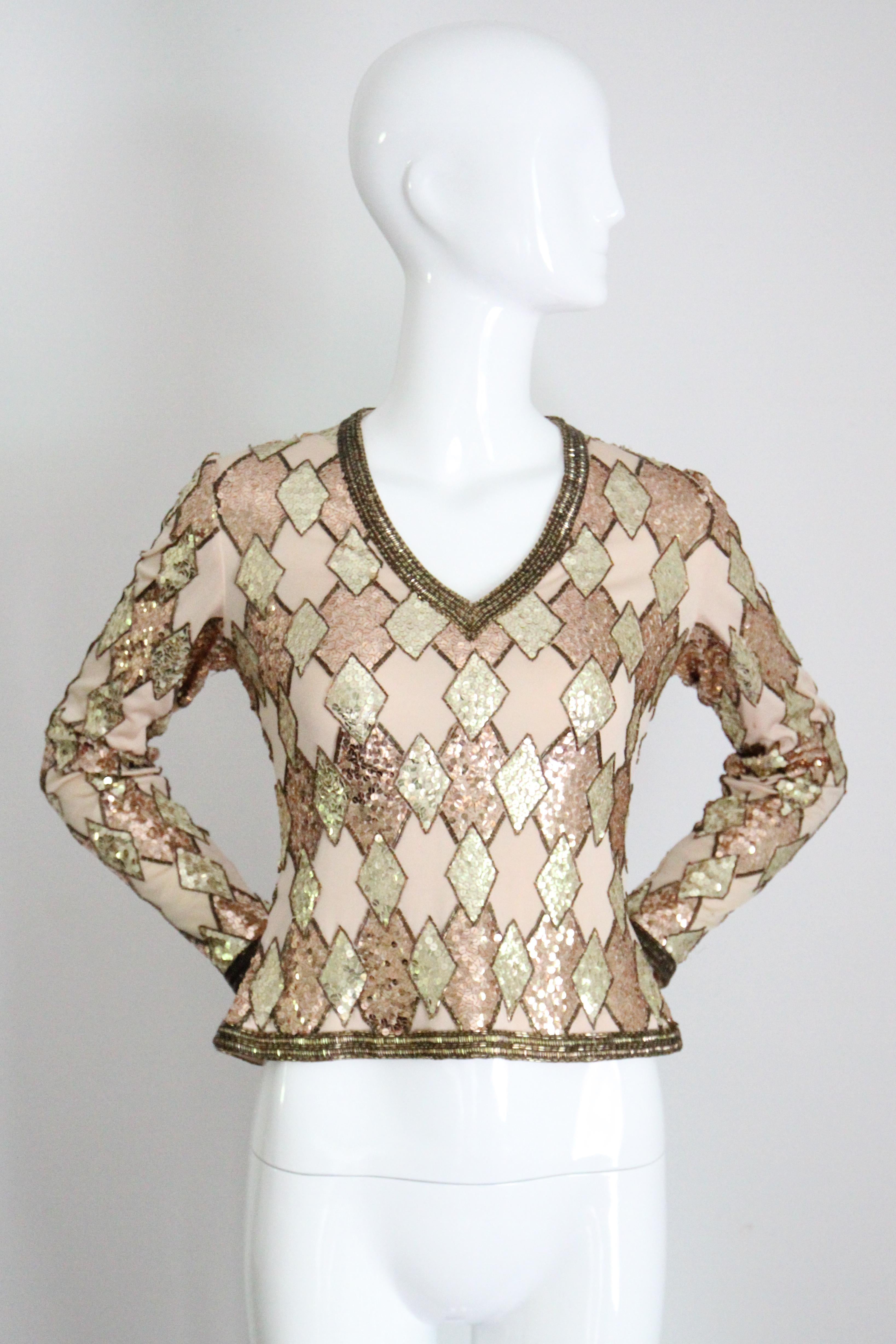Rendered in rose gold and gold sequins, set off by gold toned glass bugle beads, set against a champagne coloured jersey base, this original 1960's blouse is just the perfect touch of sparkle to add to your cocktail wardrobe. 

The V shaped neckline
