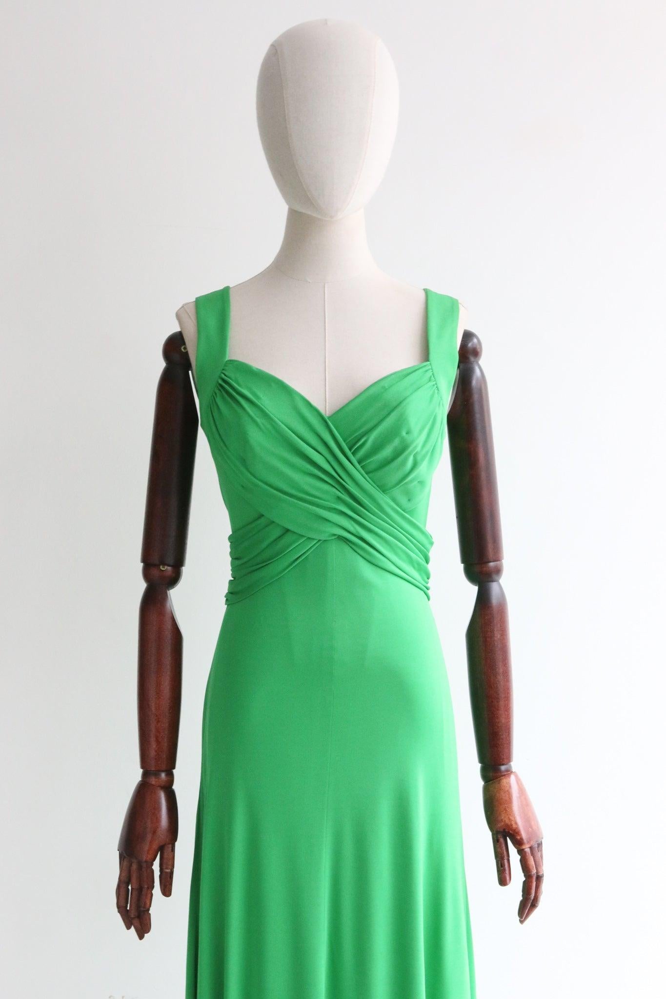 This truly mesmerising late 1960's absinthe green jersey dress, is the perfect statement piece for your wardrobe.

Her deep V shaped neckline is framed by wide shoulder straps and a sleeveless cut. Her fitted bodice is set off by pleated panels that