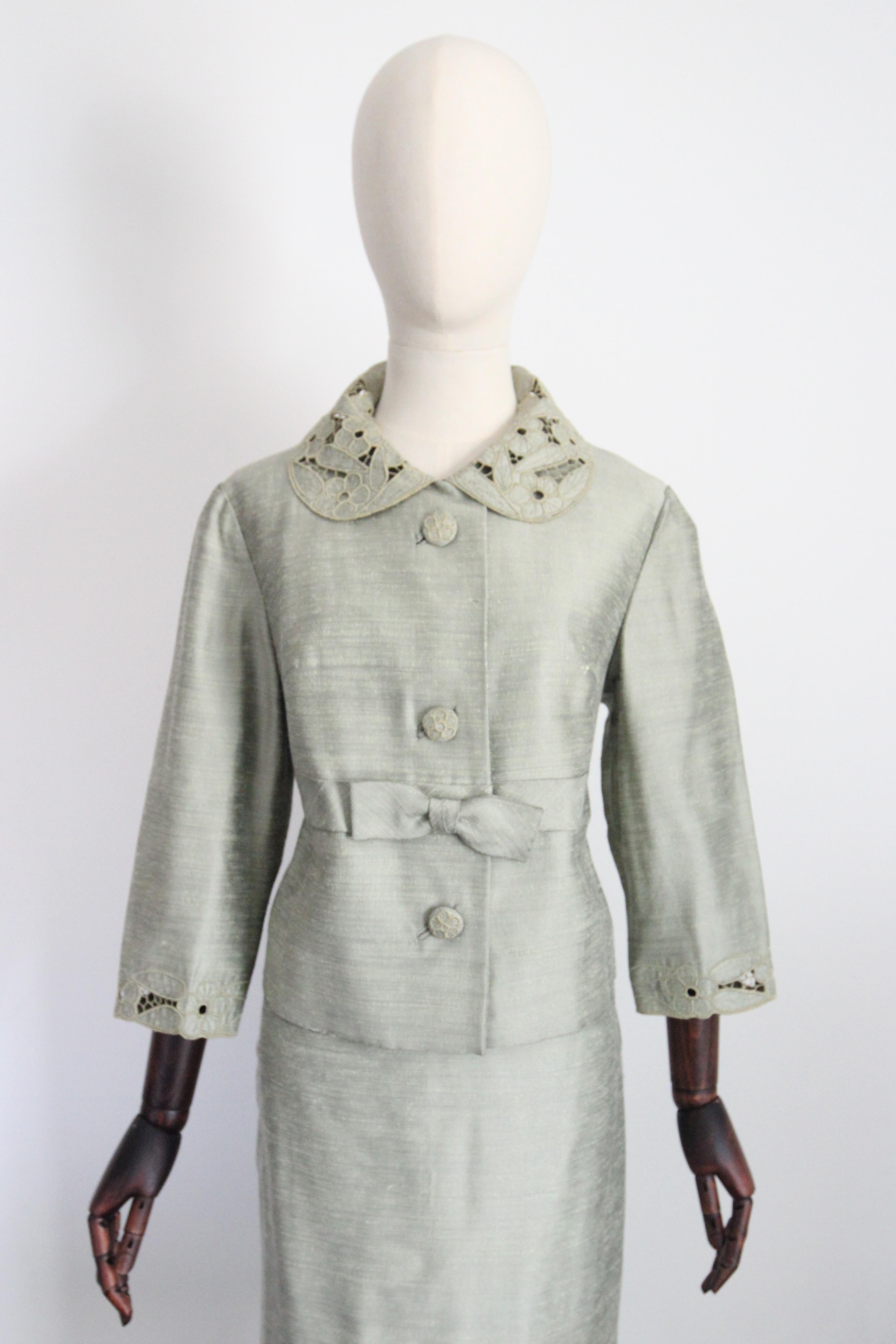 A classic silhouette rendered in the softest shade of sage green silk, with embroidered lace accents, this original 1960's skirt suit is just the perfect addition to your tailored wardrobe.  

The rounded neckline is framed by a Peter Pan collar,
