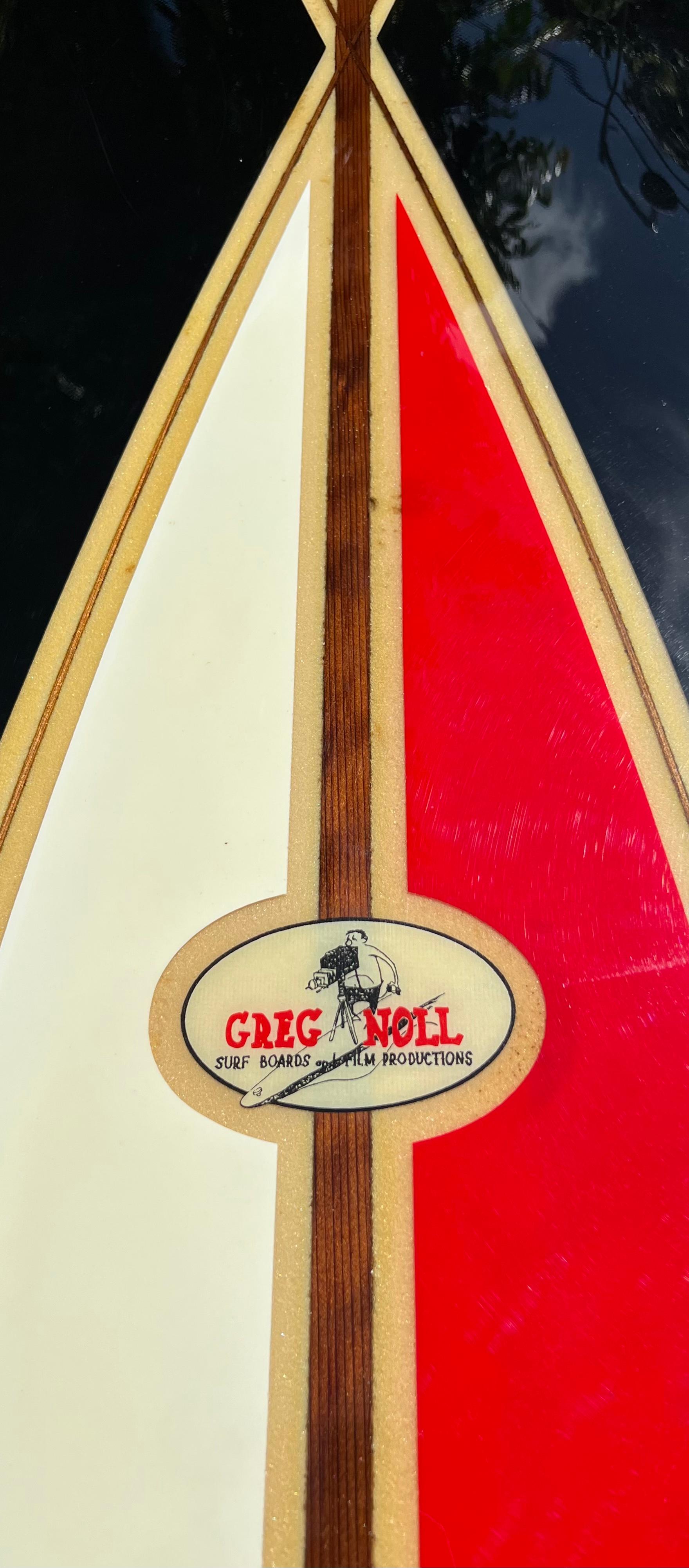 Mid-1960s Vintage Greg Noll curved “S” stringer longboard. Features uncommon curved redwood stringer design complimented by black, white, red color panels. Shaped under the famed Greg Noll Surfboards & Film Productions label, created by the late