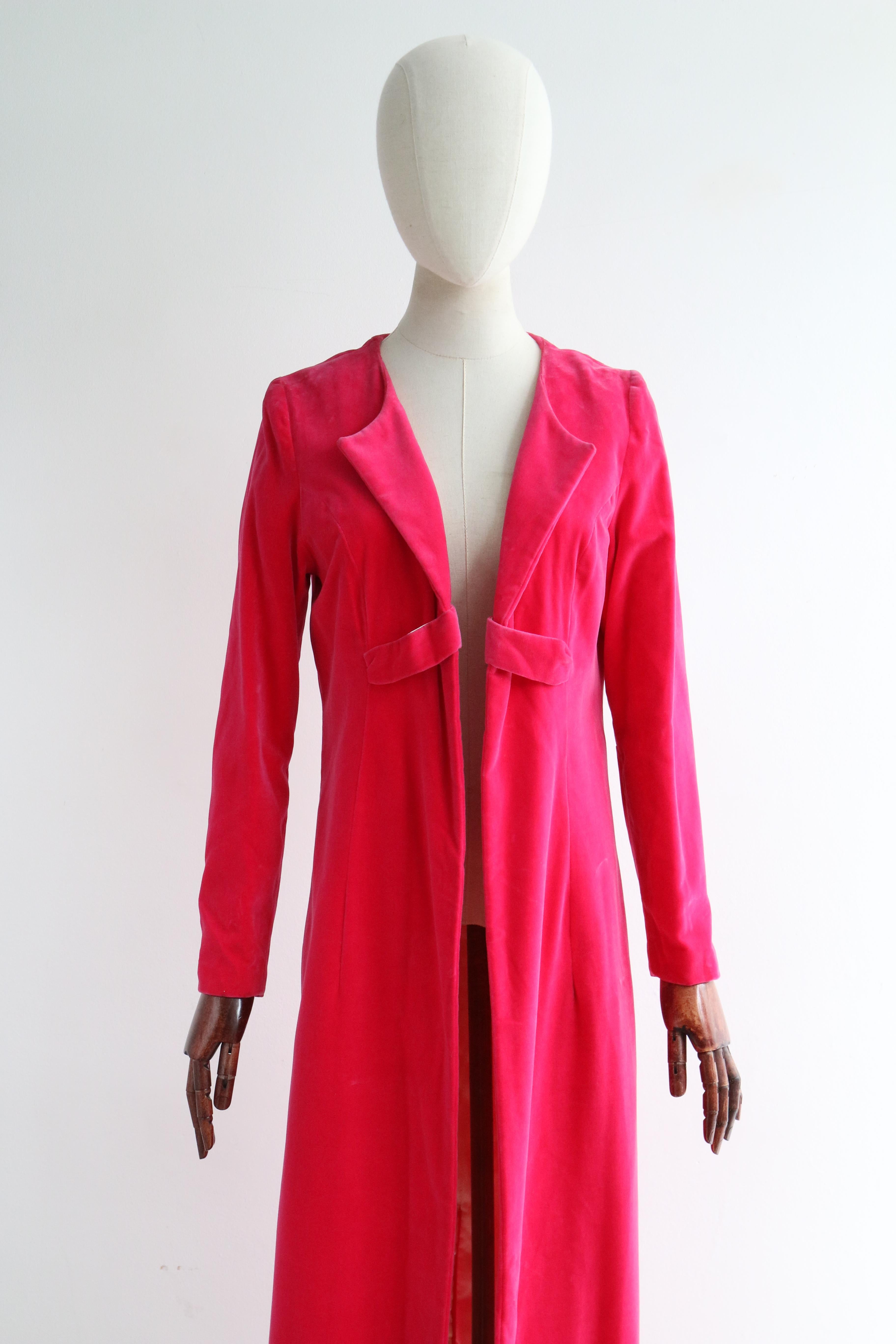 This truly vibrant 1960's Schiaparelli pink velvet evening coat, lined in cream rayon satin, is just the statement piece for your wardrobe.  

The open cut neckline of the coat is framed by curved pointed lapels that join the front of the