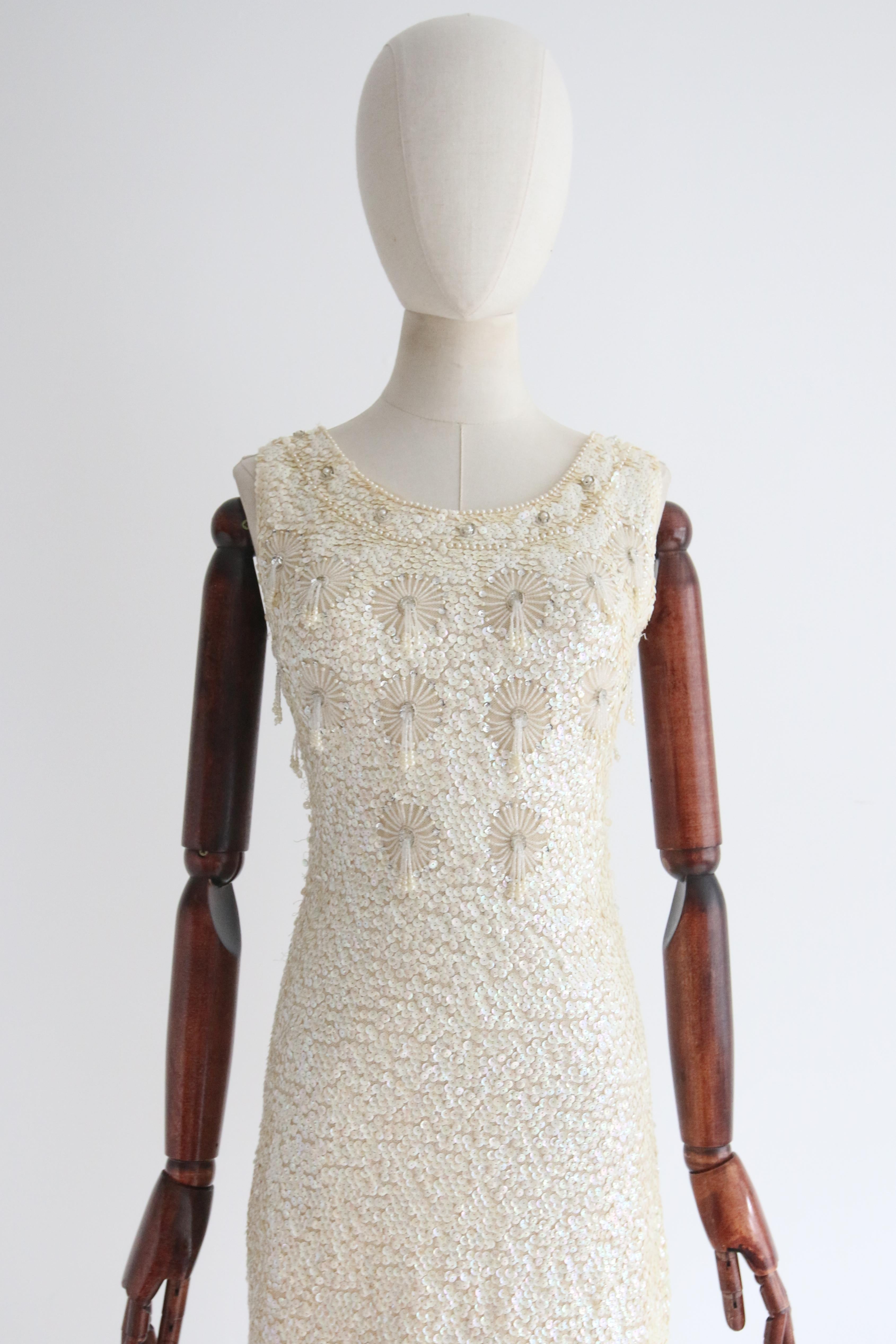 This breathtaking 1960's cream knitted wool dress, embellished in its entirety with cream iridescent sequins, and finished with floral beaded details, is the perfect piece for a sparkling occasion.

The rounded scoop neckline of the dress is framed