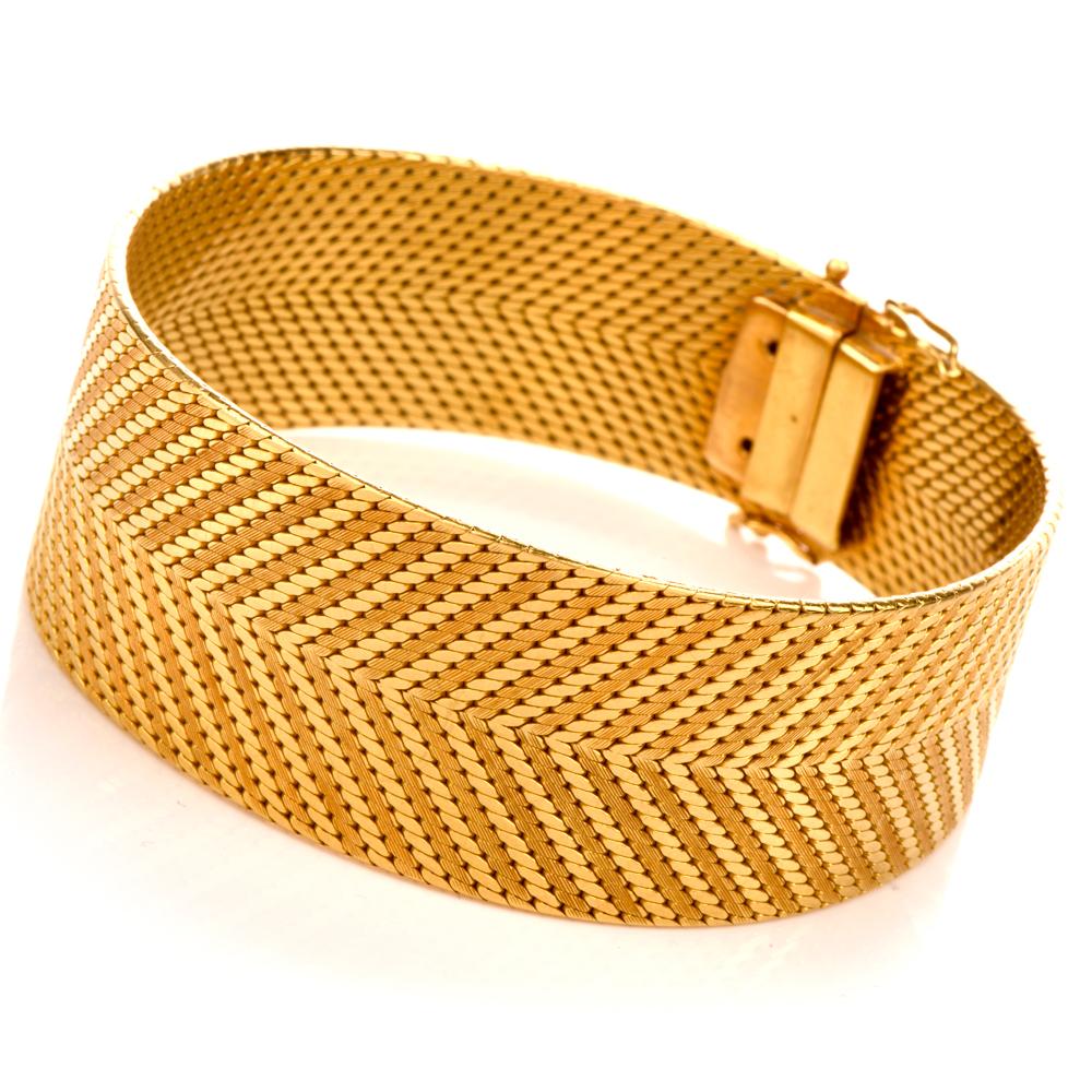 This desirable bracelet is Italian crafted in 18-karat yellow gold, weighing 81.5 grams and measuring 7.50” around the wrist x 1 inch (24mm wide ). This flexible bracelet displays a braided arrow texture. Secures with tongue in groove and safety