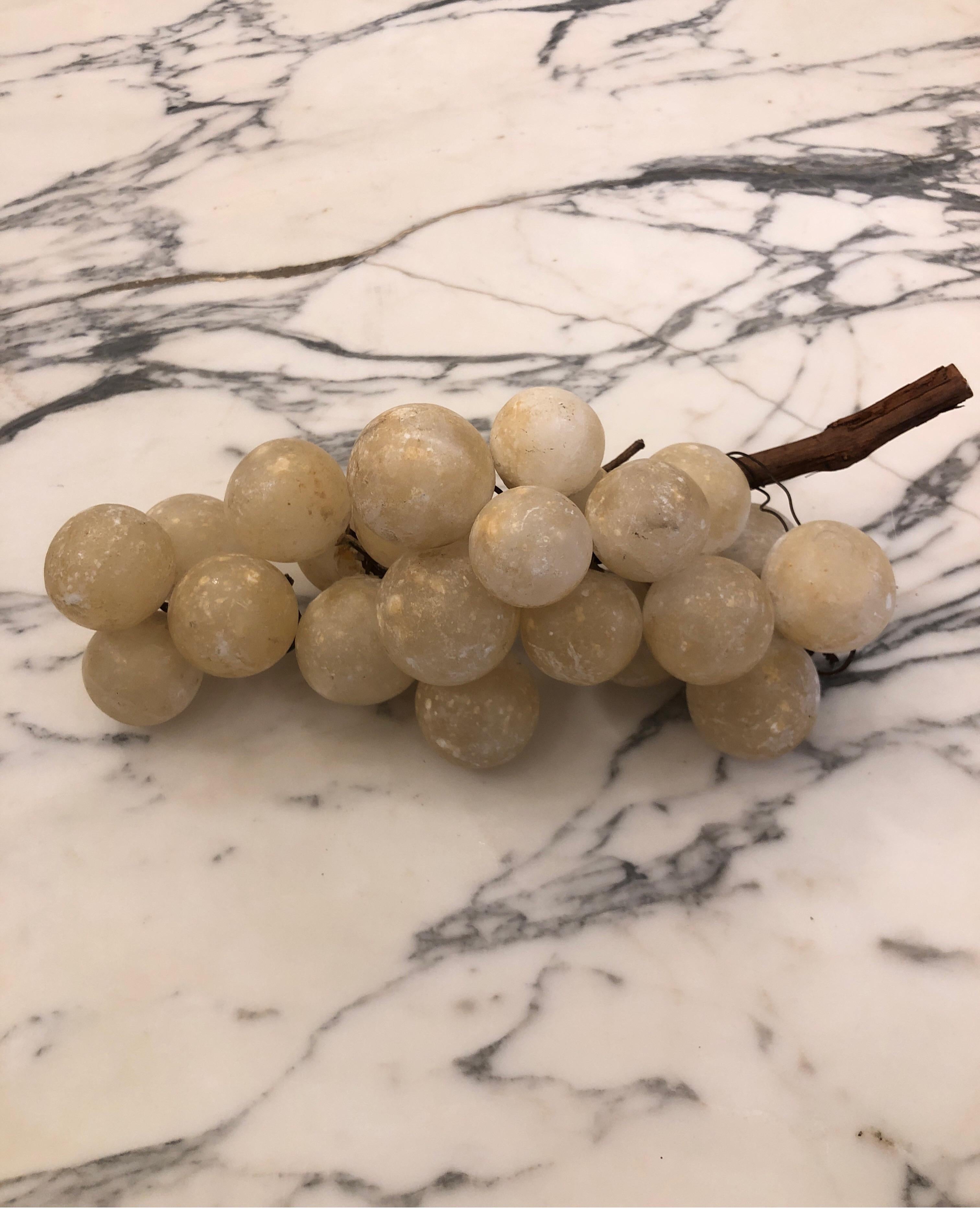 Large cluster of grapes made of aged ivory white marble. Two different clusters attached to one branch.