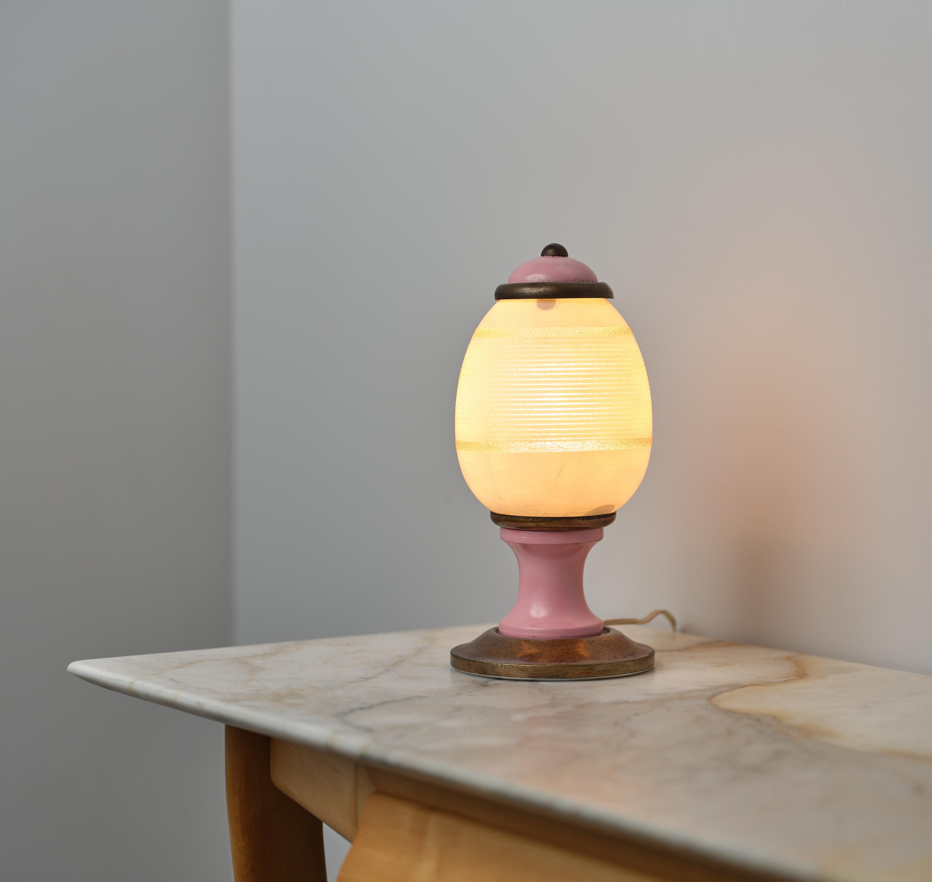 This table lamp, dating back to the 1960s, is a remarkable example of modernist design. Originating from Italy, the piece showcases the era's aesthetic with clean lines and a functional form. The lamp features a dual-material construction: the base