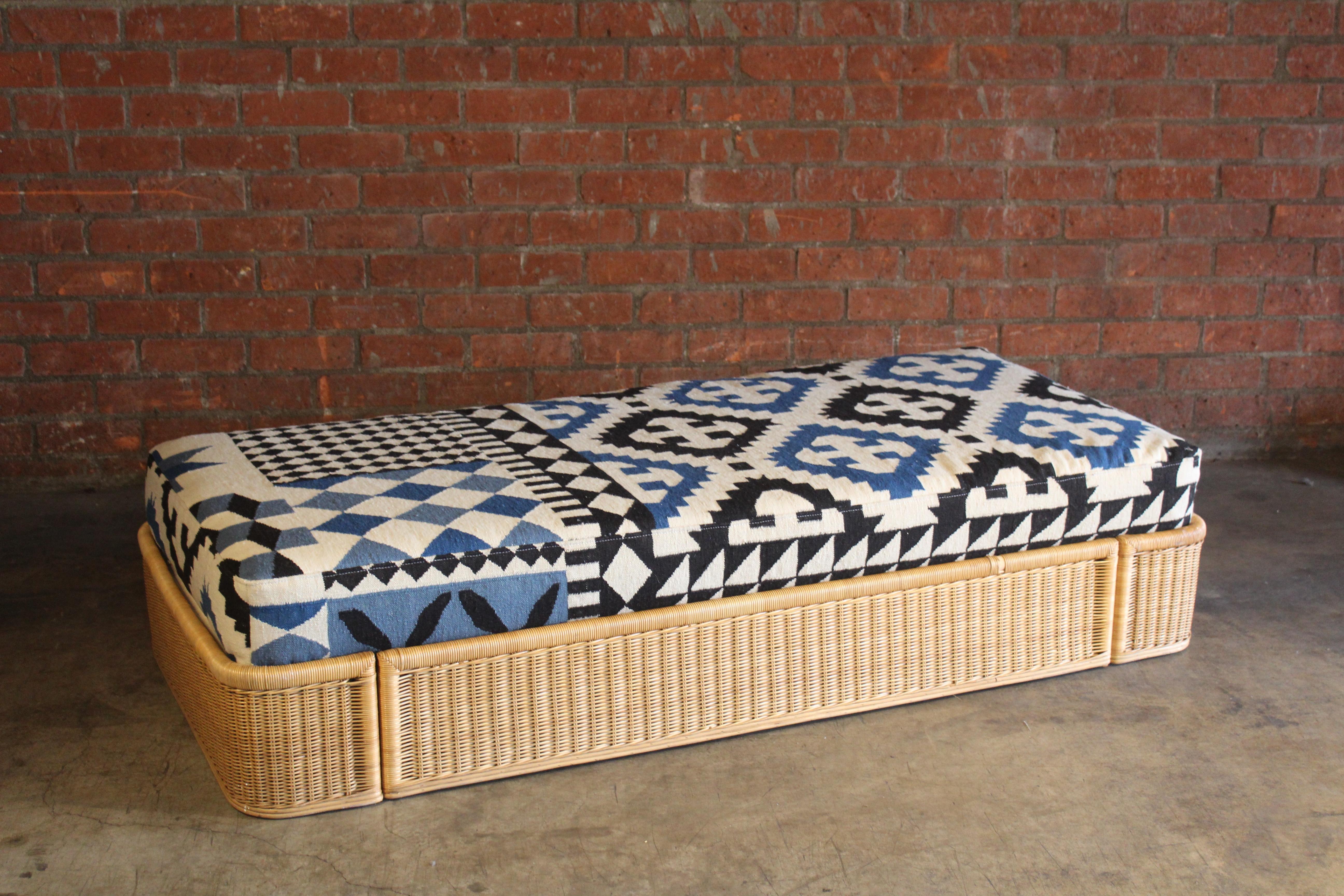 A vintage Italian 1960s wicker and bamboo daybed, upholstered in a vintage flatweave wool rug. The rug was professionally cleaned prior to upholstery. Daybed is in good condition with minimal wear. There is one small area with broken wicker.