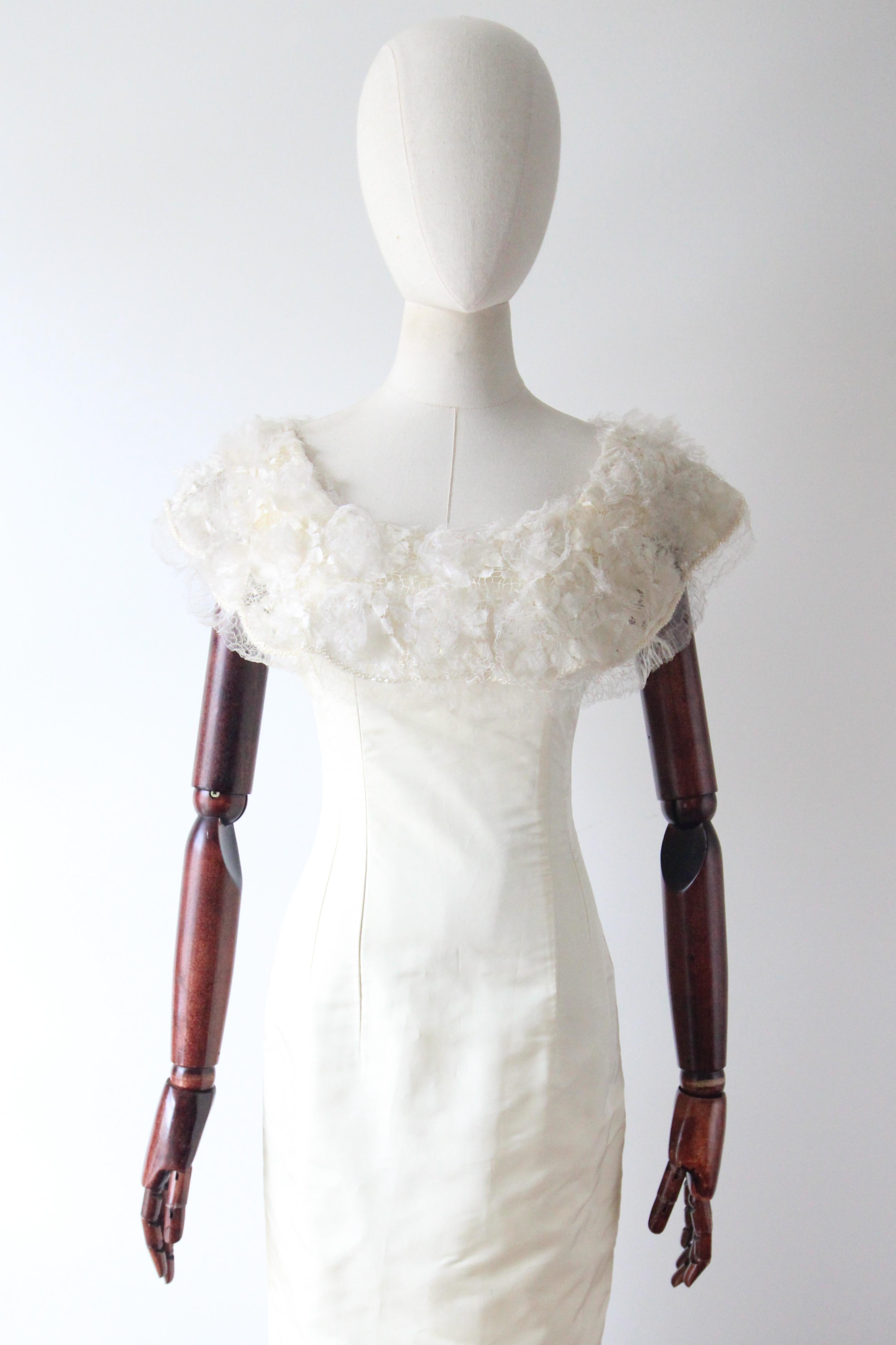 Une silhouette classique avec un col en rayonne crème et organza ivoire, agrémentée de perles de verre facettées irisées, de dentelle et de perles de verre clair, cette robe vintage des années 1960 est la pièce parfaite pour une occasion spéciale.