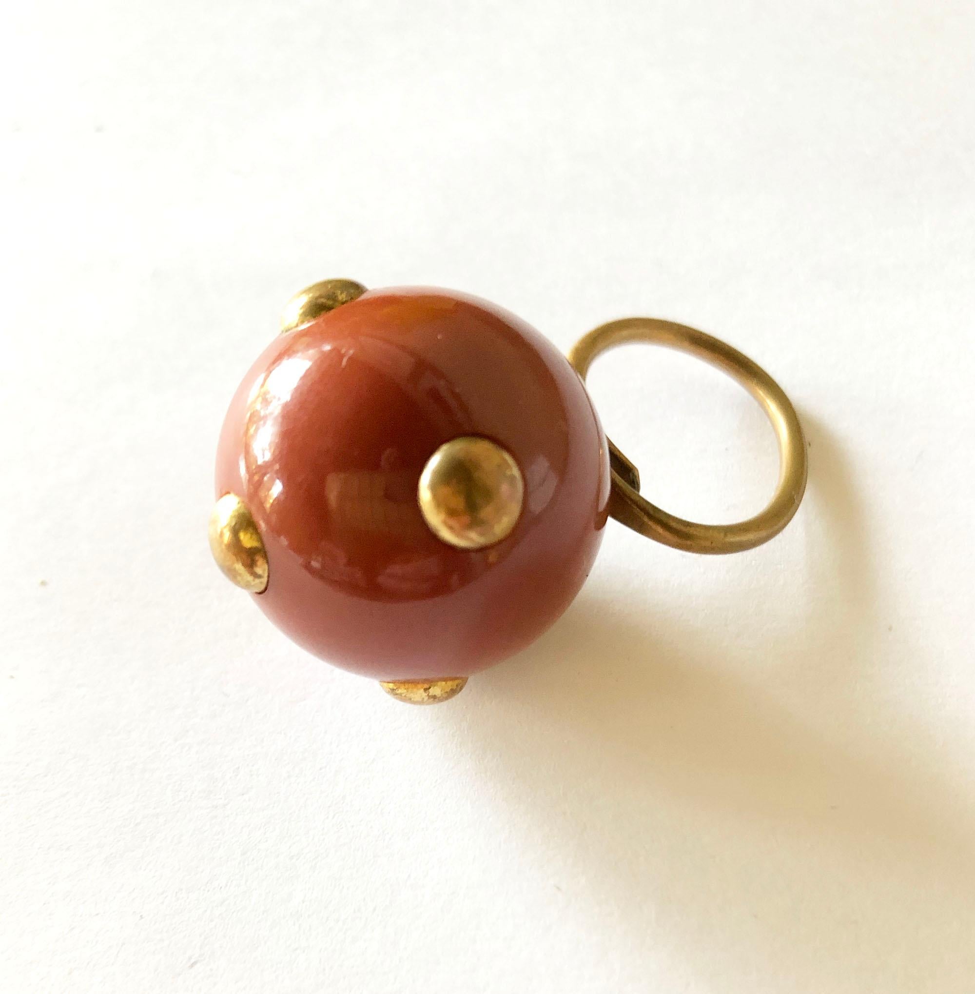 Vintage 1960's mauve bakelite ring with brass studs made by Kenneth Jay Lane, New York.  Ring is currently a finger size 6.5 and is slightly adjustable and a bit out of round. Ball is 1