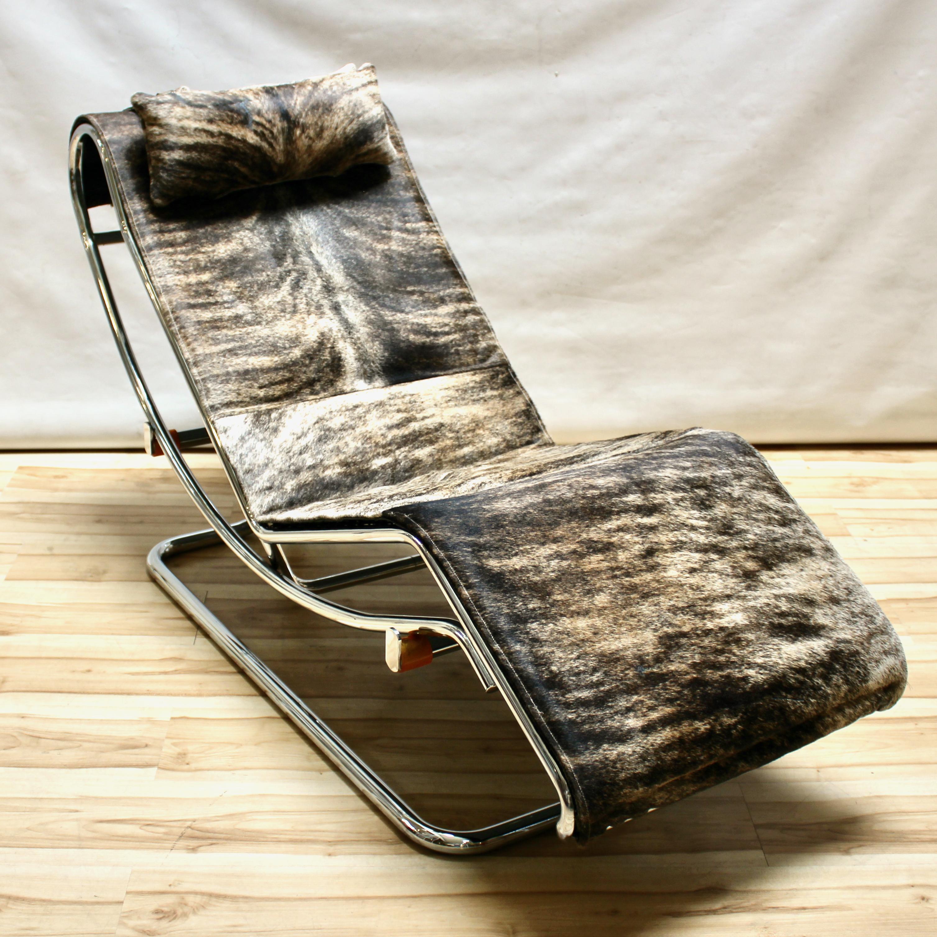 Vintage 1960s lounge chair in the style of Le Corbusier’s LC4 chair. The chair has been upholstered in cowhide and is fully adjustable. Both the seat and base are chrome, and there is an adjustable upholstered pillow. In excellent